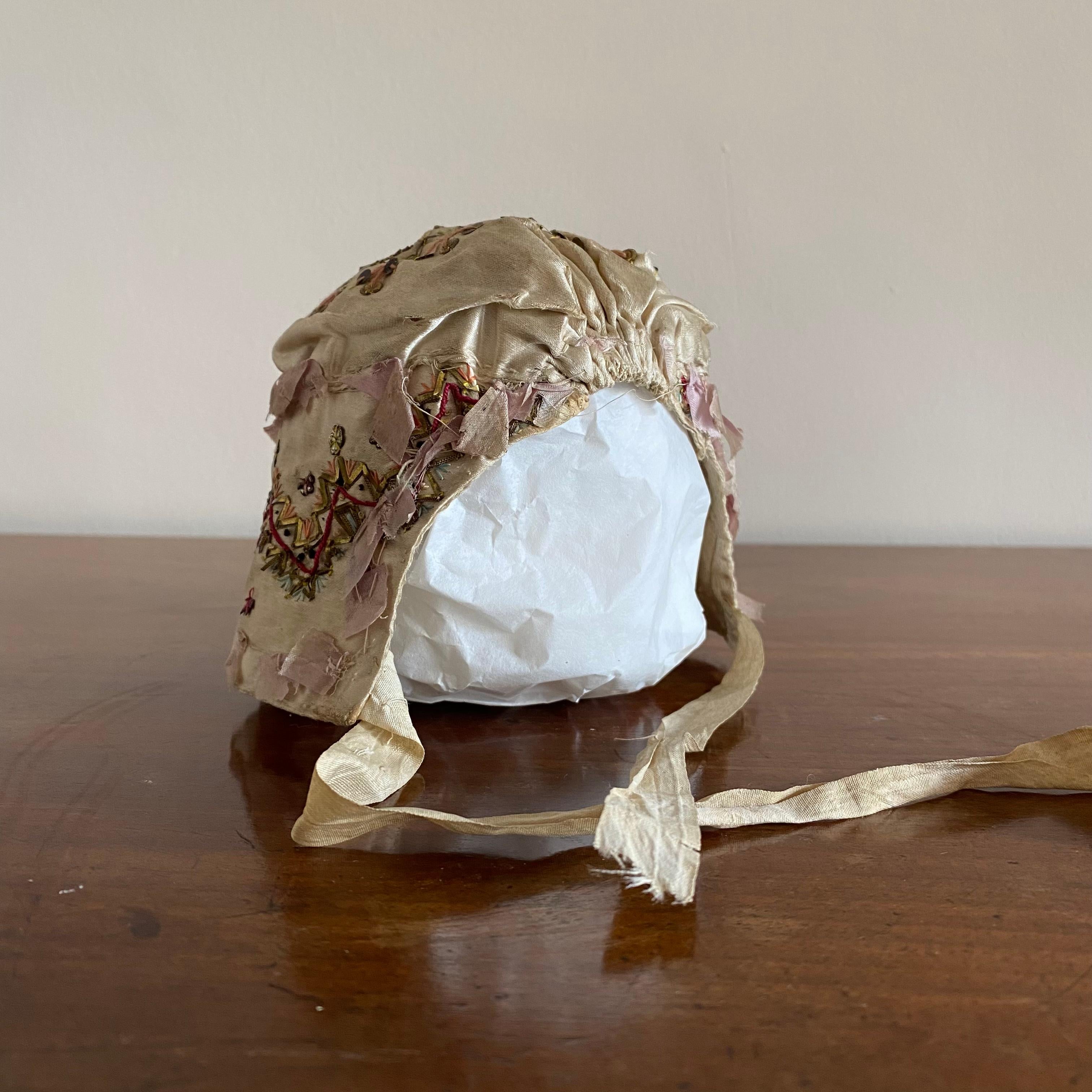 Early 19th Century English Silk Baby Bonnet.

A wonderful 19th century silk baby bonnet with sequins and wirework detail. Retaining its original tying ribbons. Circa 1800.

Measures: Height: 10cm

Width: 9cm

Depth: 9cm.