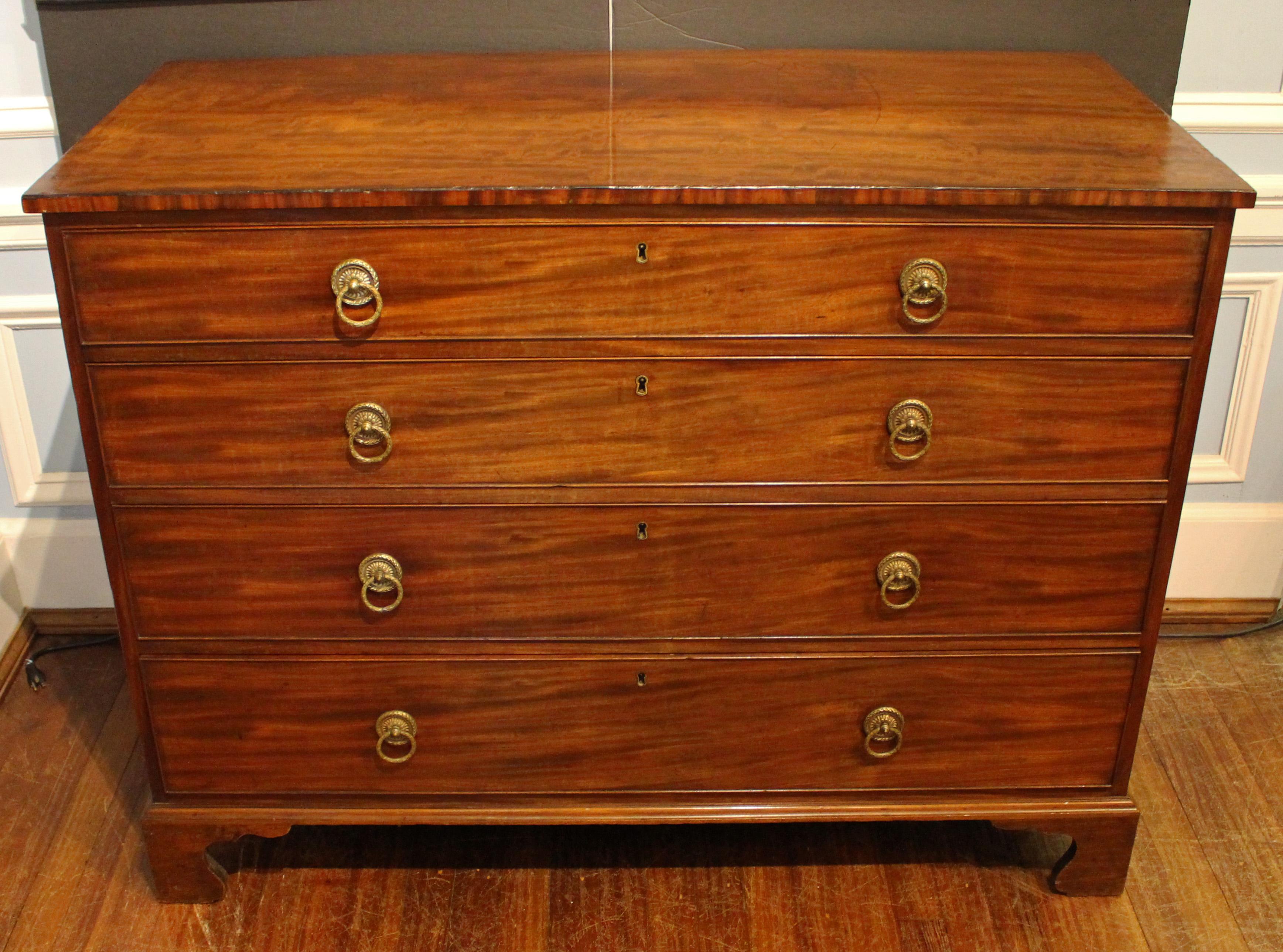 Late 18th-early 19th century Georgian chest of drawers. Comprised of 4 graduated drawers with well cast brass laurel motif ring turned pulls. Cockbeaded drawers, raised on stout shaped bracket feet. Top with a moderate amount of scrapes, marks &