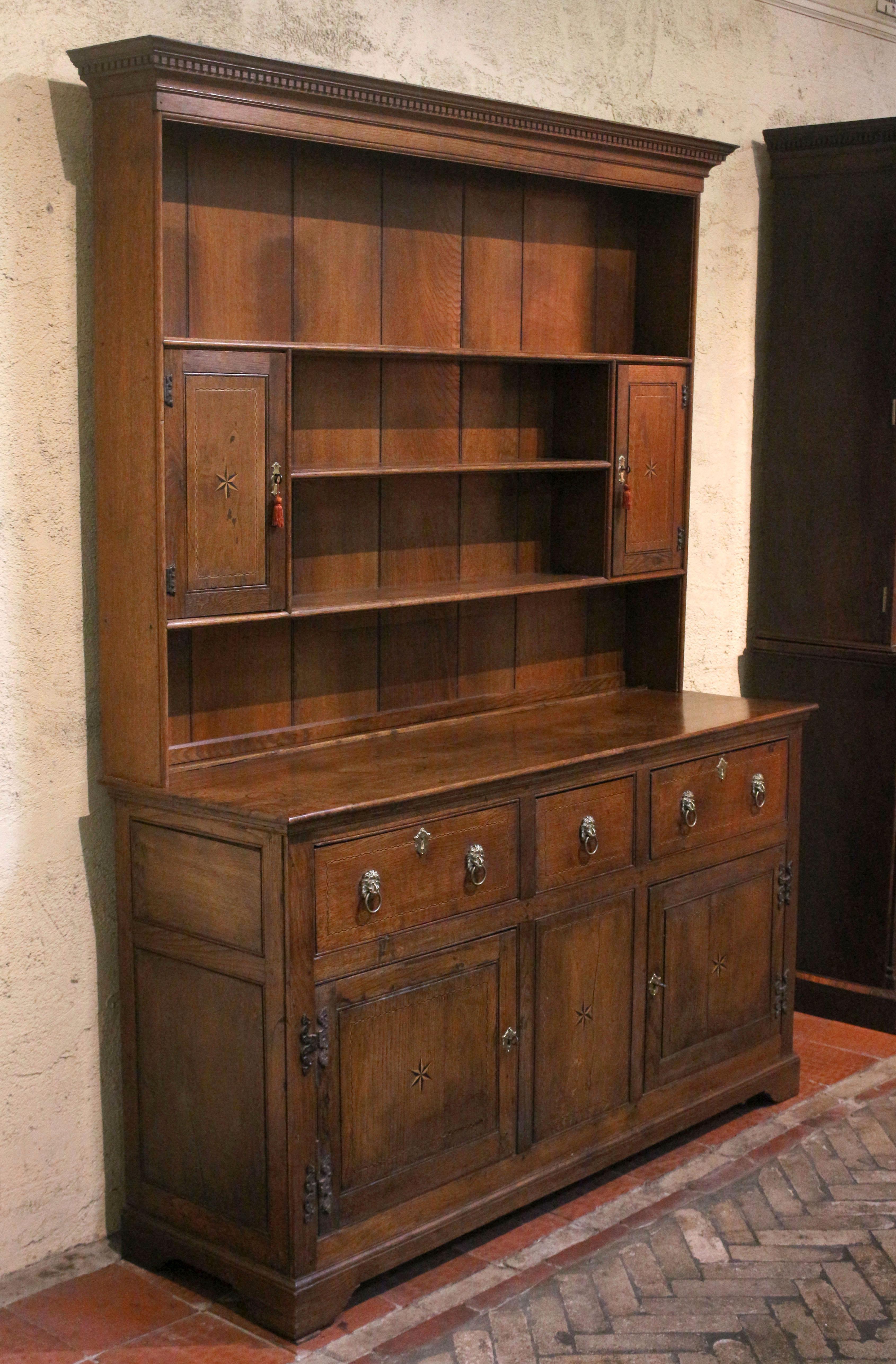 Late 18th-early 19th century oak dresser, English. Late Georgian period. The upper shelf section with spice cabinets & dentil molded crown over the base with central short drawer over blind panel flanked by drawers over cabinets. Contrasting ebony &
