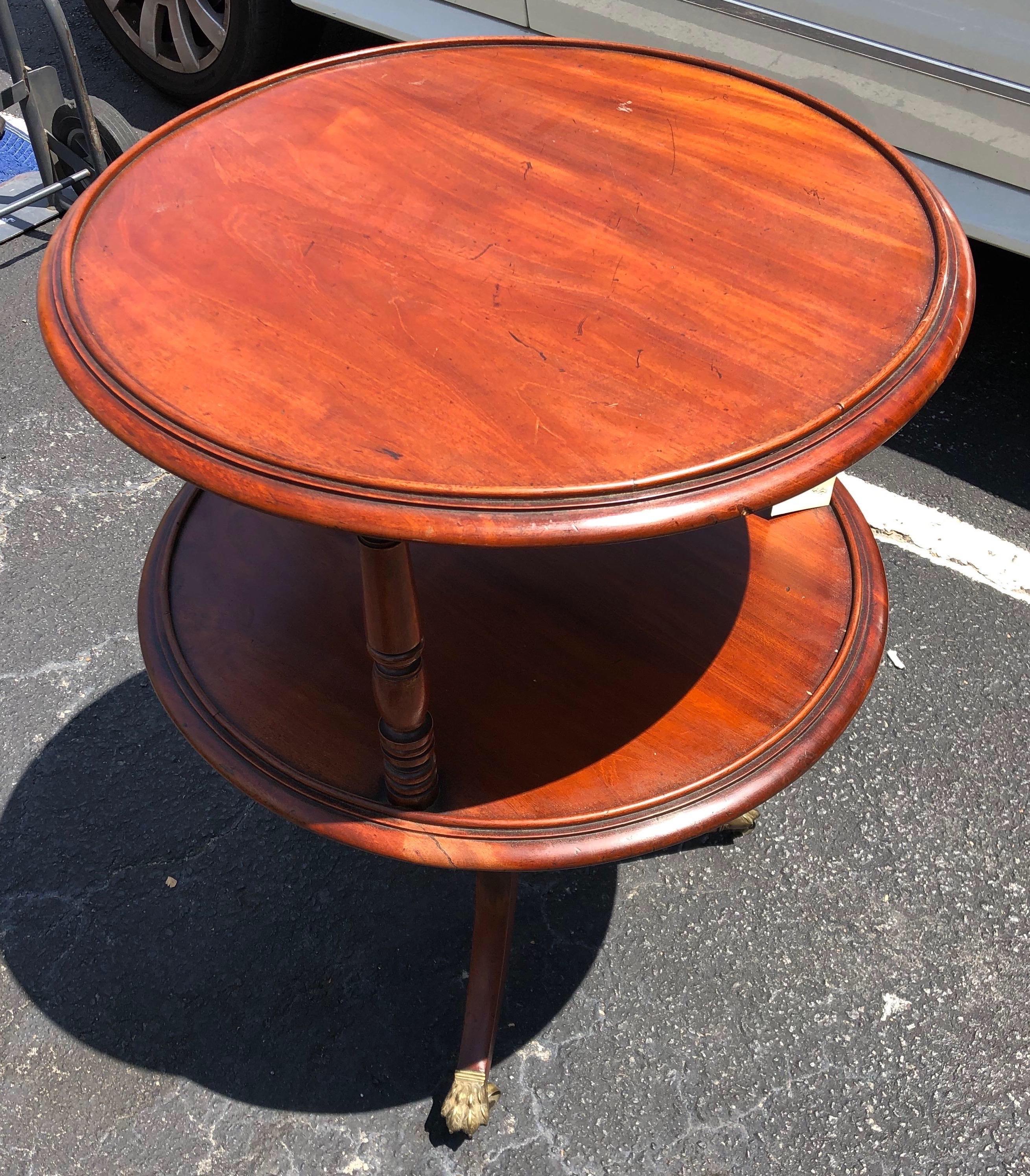 Late 18th-early 19th century Georgian mahogany two tier dumbwaiter with molded shelves, turned supports, sabre legs resting on original brass paw feet castors.

Great color and patina all around. Nice size- height is good for a side table.