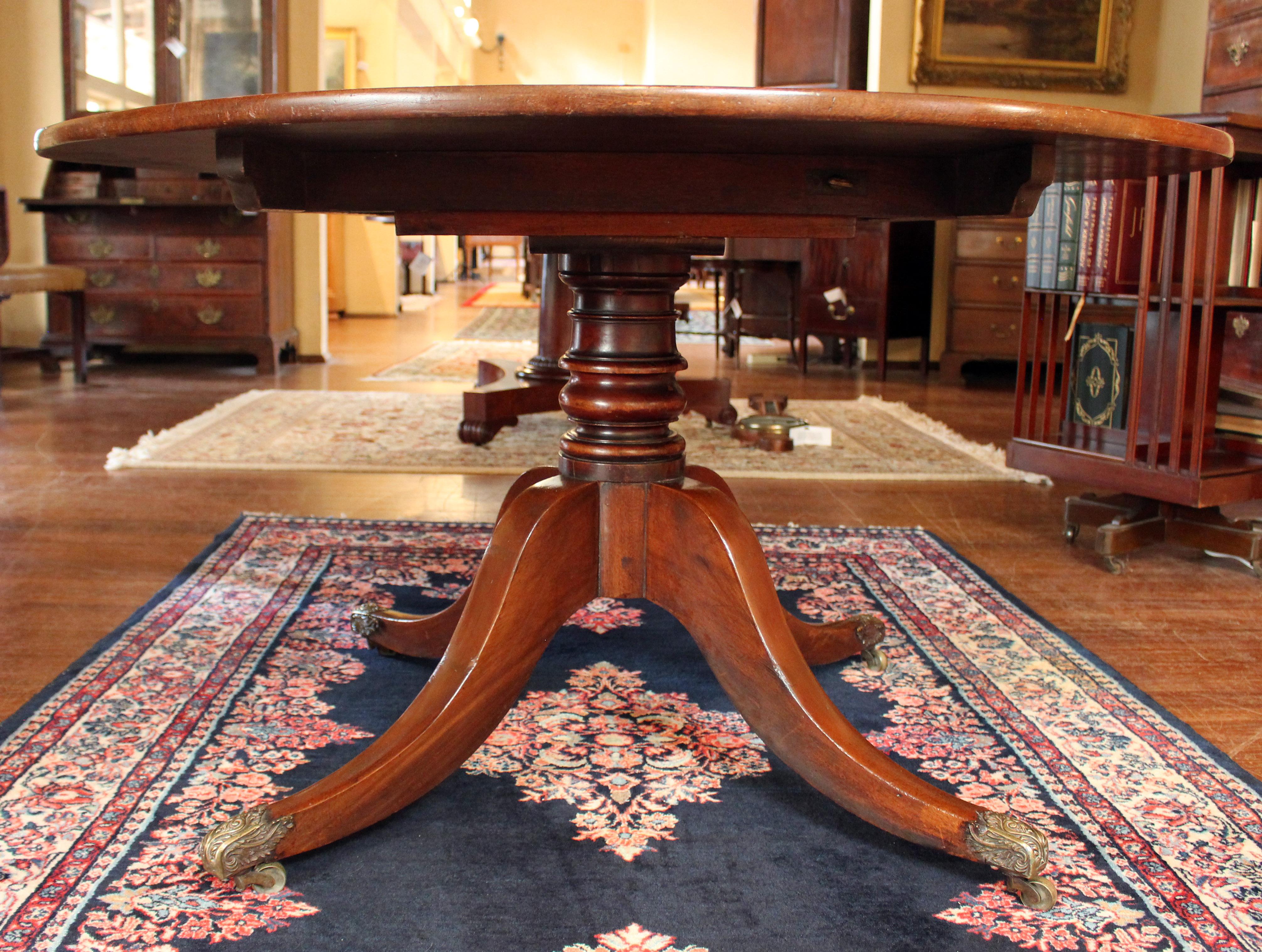 Late 18th-early 19th century Georgian round breakfast table or center table. English. High quality mahogany. Solid, well turned pedestal shaft to shaped splay quadraped leg base ending in outstanding quality heavy brass neoclassical acanthus motif