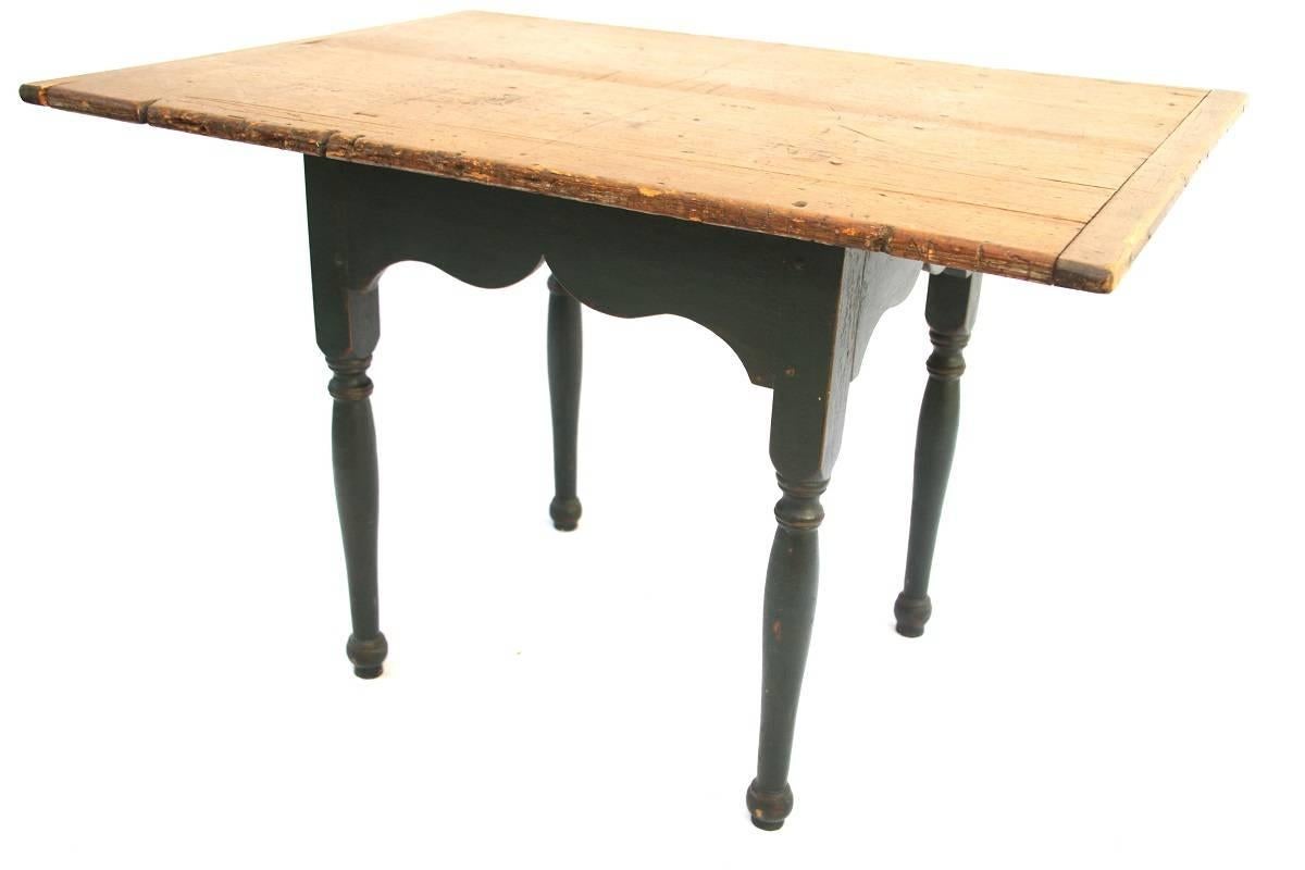 Maple and pine two-board top tavern table with breadboard ends and scrubbed surface above a shaped skirt with old, if not original paint, and pegged construction joining turned legs.
 
Dimensions: 27” H x 41” W x 29 ¼” D
 
Other: 5” Overhang on