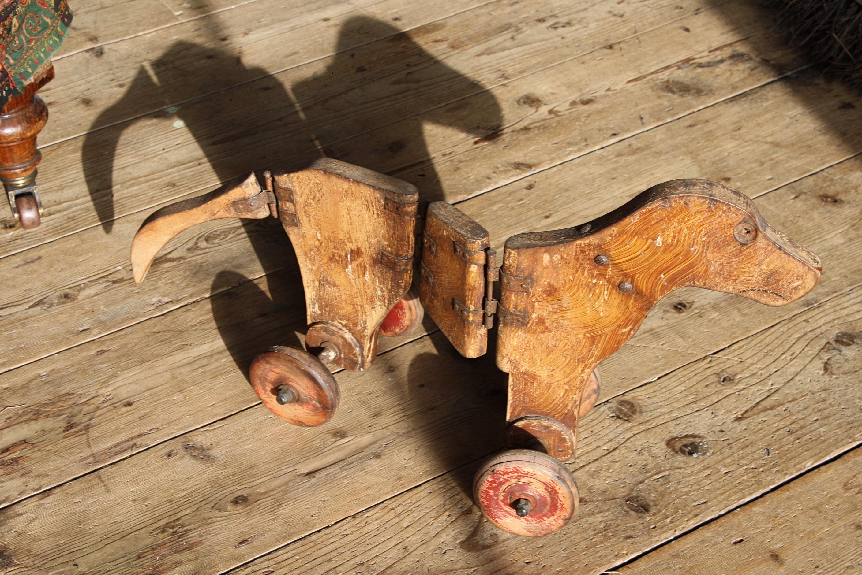 A wonderful early articulated pull along dog, possibly late 18th century in age if not early 19th century 

Original wrought iron pin hingers and scumble painted finish, with what of been letter box red wheel, now heavily faded with time. Iron