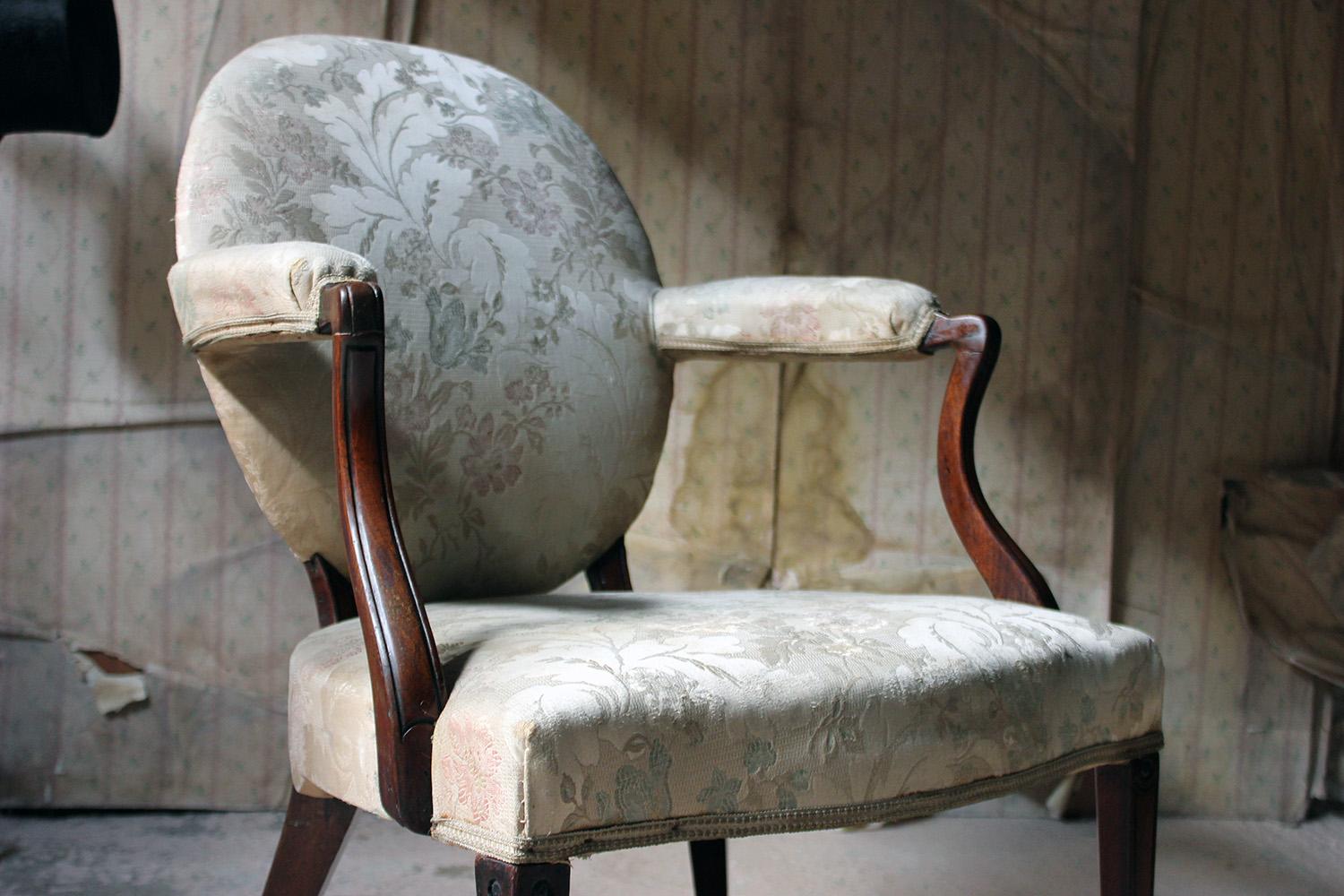 The Scottish Georgian period open armchair in the Hepplewhite taste, in faded floral upholstery, having swept padded arms and an oval back, to tapering front legs with bullseye patarae and spade feet to unusual geometric rear legs, the whole