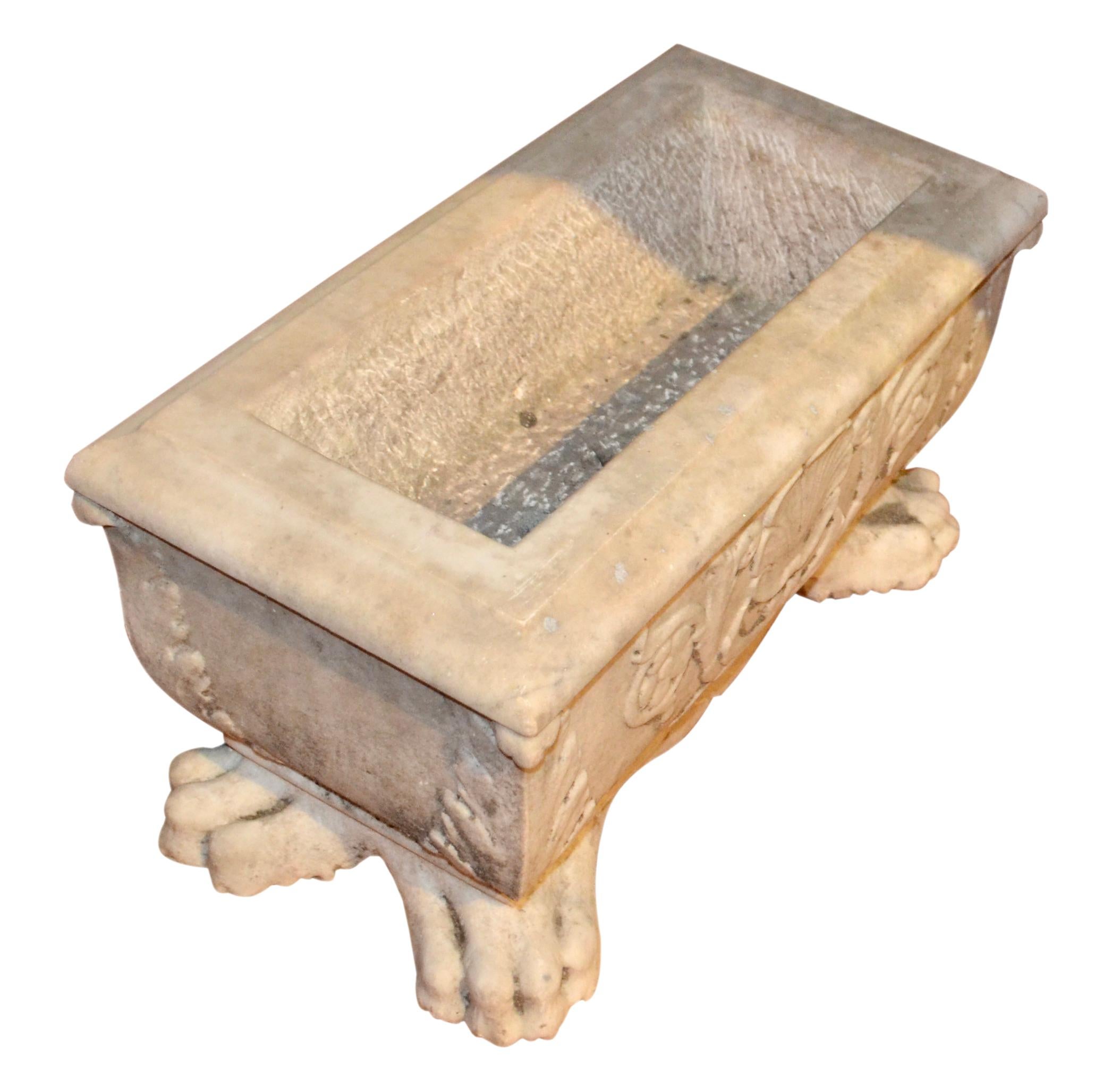 This classic planter is carved from a single piece of Carrara marble.  The wasted shaped pot sits on four large lions paw feet each of which are topped with a large carved acanthus leaf which continues up each corner to the top of the planter.  The