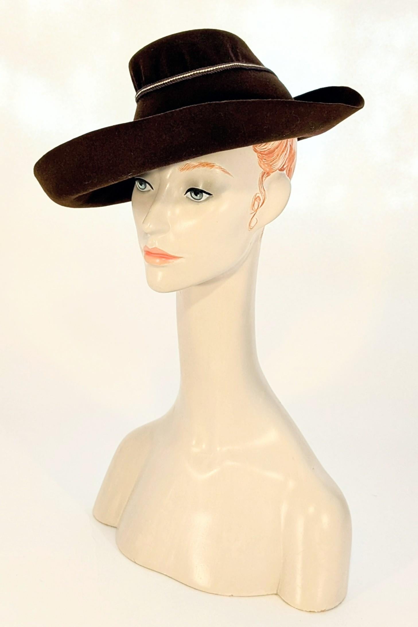 Questo cappello favolosamente elegante risale alla fine degli anni '30/inizio anni '40. Realizzato in lana marrone cioccolato e impreziosito da una lavorazione a cordoncino marrone e avorio che accentua la forma e la struttura del cappello. Ha un