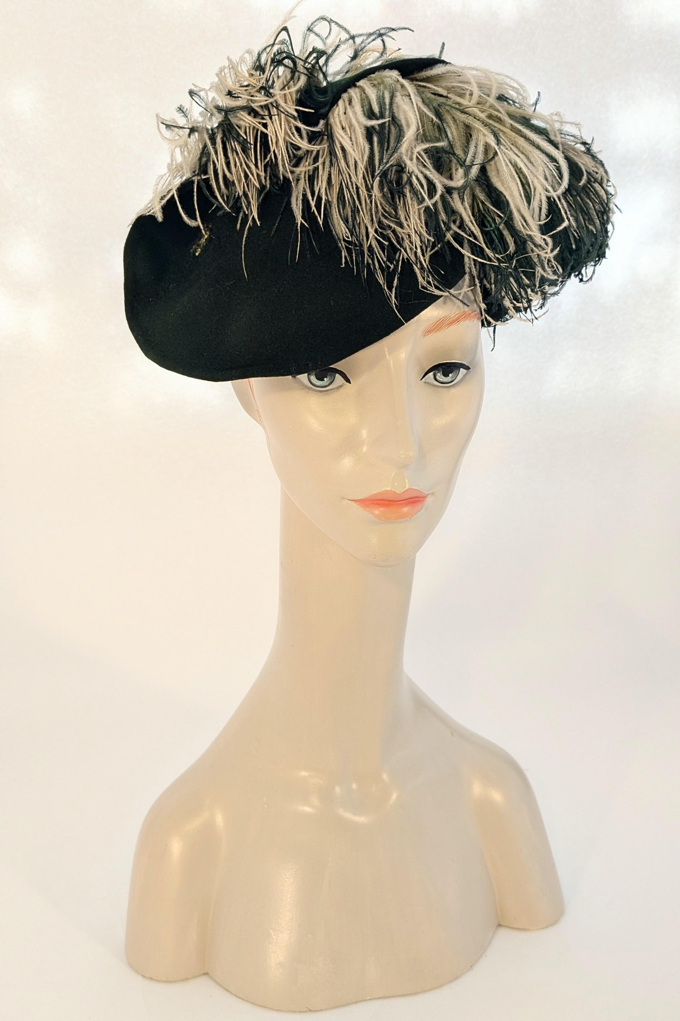 This fabulous late 1930s/early 1940s hat is made of a deep forest green wool felt that is formed with sweeping shapes that the ostrich feathers bloom out of. The feathers are dyed a few different colours, some are ombré from a vibrant green at the