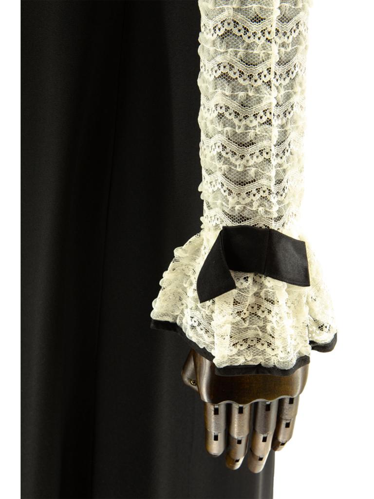 Evening dress inspired by a mens tuxedo shirt. Dress features white a lace top with lined bodice, the sleeves are left unlined so that the skin shows through the lace. Frilled collar and cuffs with black satin bound edging and matching bows. Faux