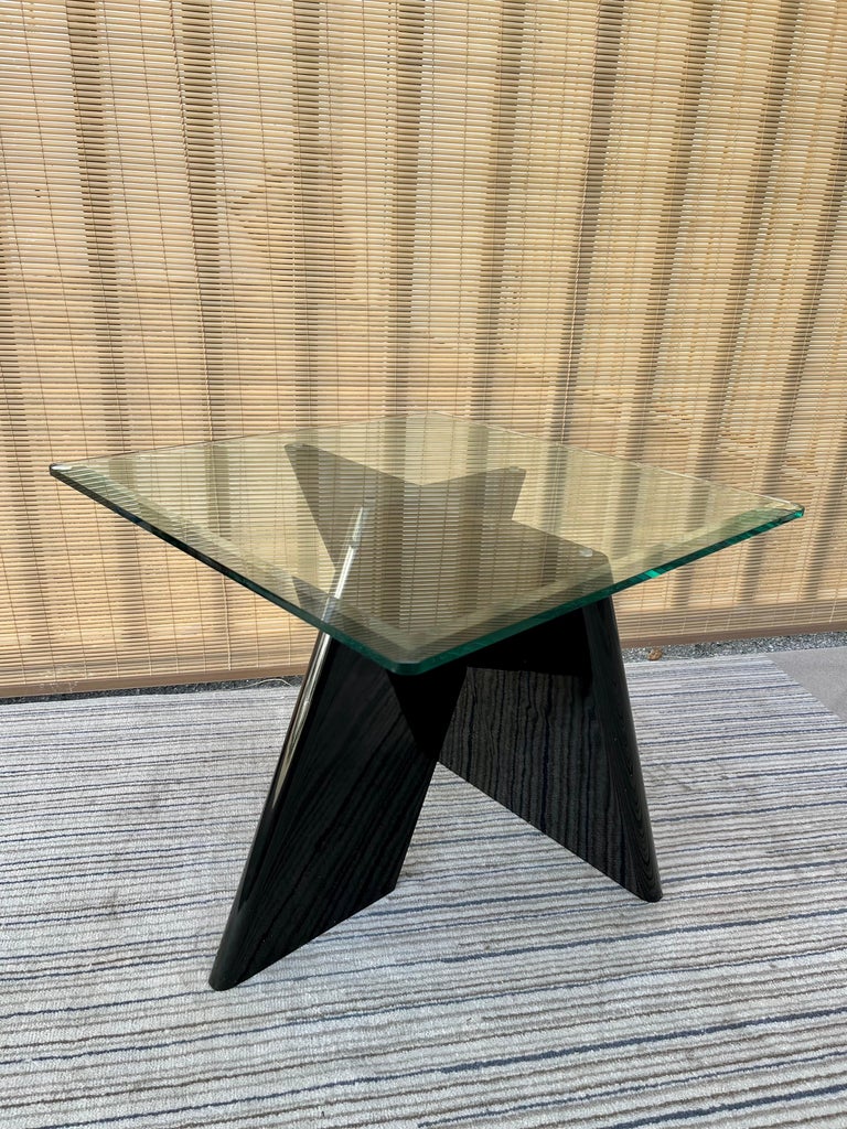 Vintage black lacquer postmodern side table. Circa Late 1970s.
Features a geometric x-shape designed pedestal with a black glossy lacquer finish, and a beveled square removable glass top. 
In great original condition with very minor signs of wear