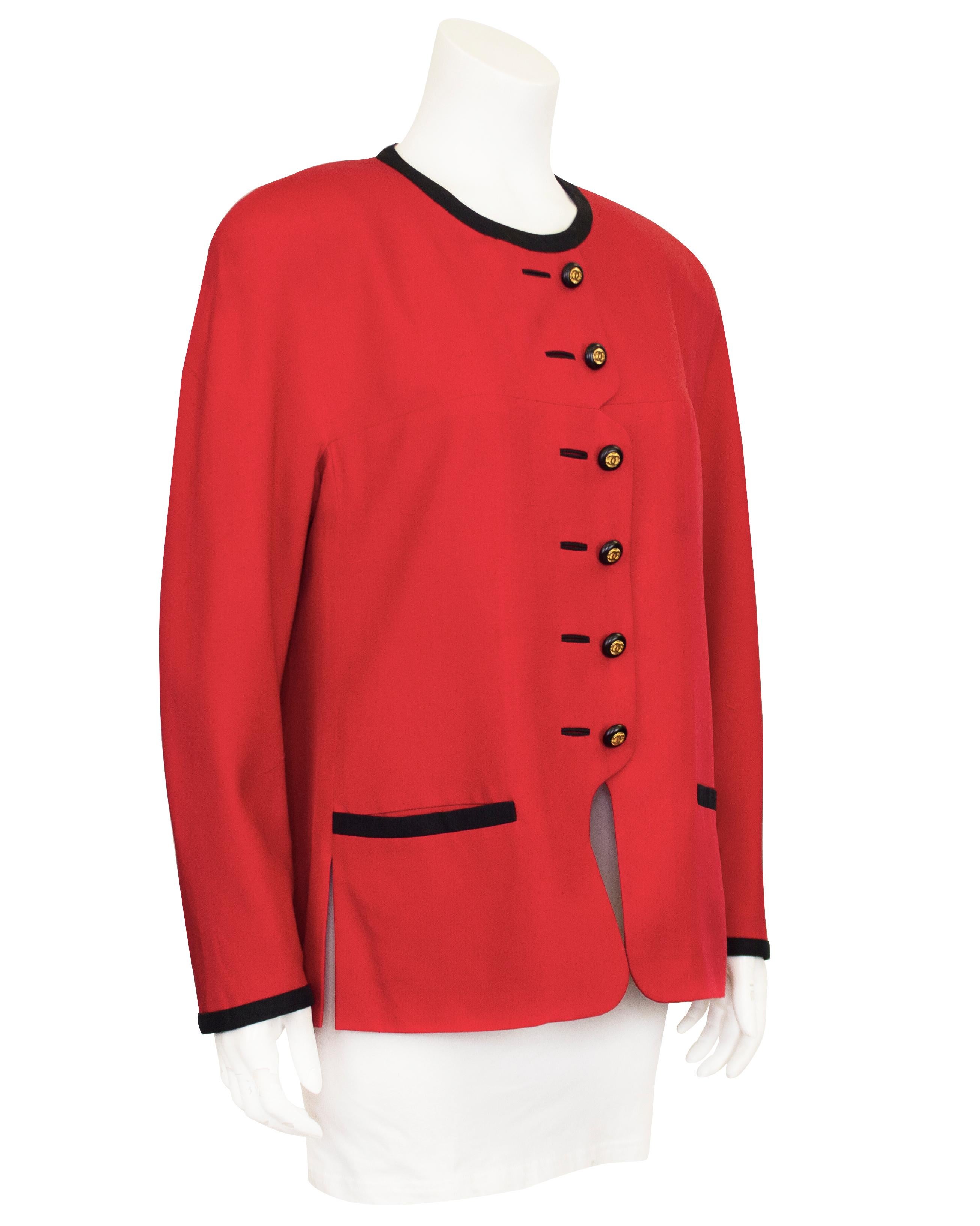 Red Chanel Shantung silk jacket from the late 1980s. The red jacket is trimmed in black along the neckline, pockets and cuffs. The buttons down the front feature a unique notch half way down and are coupled with faux button holes. The jacket fastens