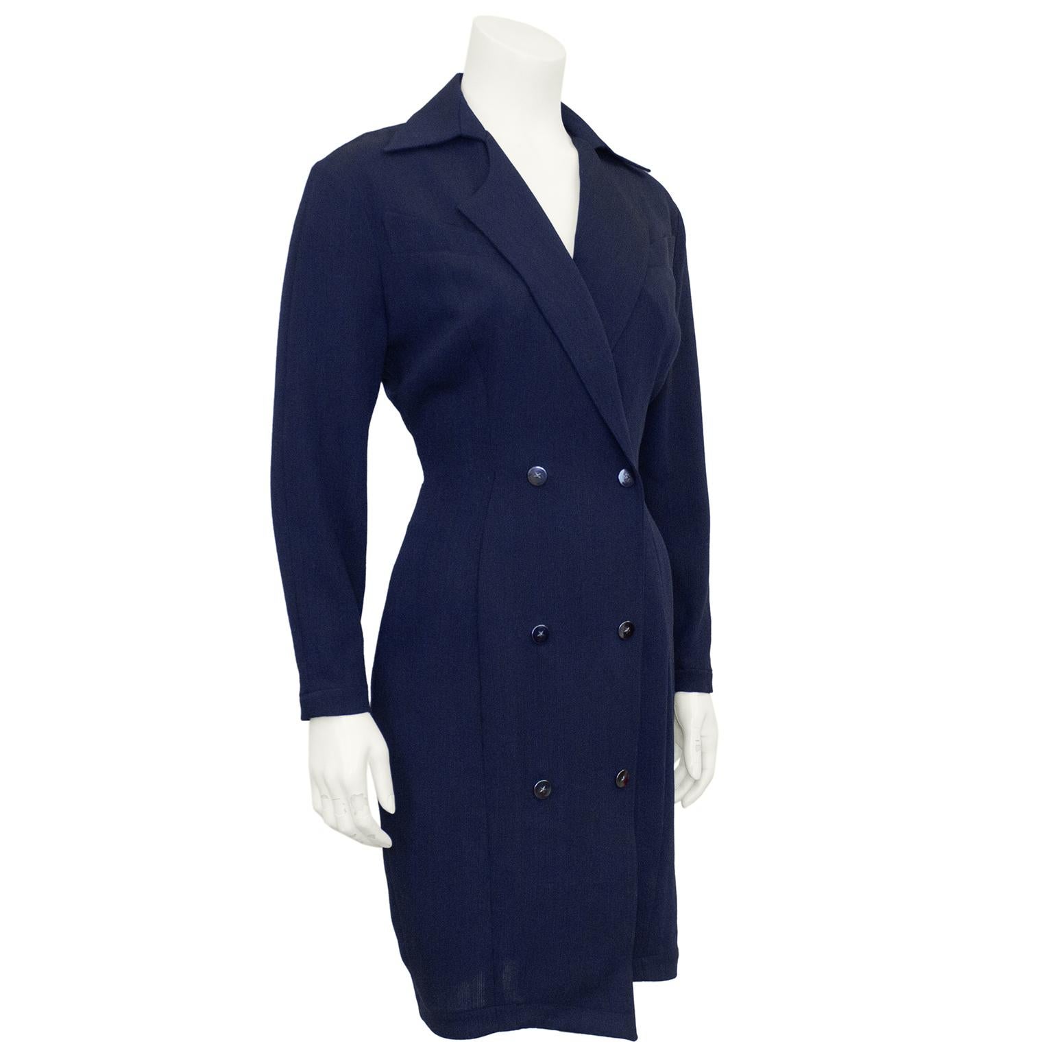 This 1980s navy blue wool coat dress is quintessential Thierry Mugler strong power dressing with its hyper feminine hourglass shape, narrow waist and broad shoulders. The double breasted dress features an oversized notched collar that creates a deep