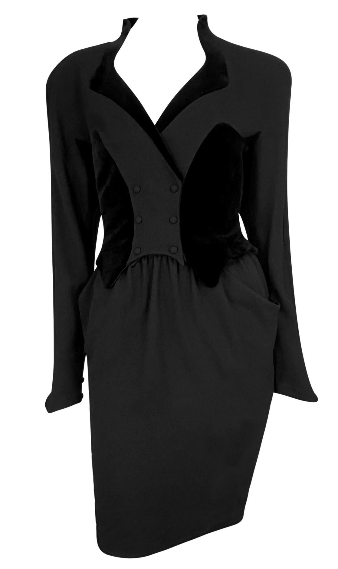 This late 1980s Thierry Mugler black midi dress features a sculptural design with velvet accents, mimicking a skirt suit. The structured silhouette includes exaggerated lapels, a double-breasted bodice, and a cinched waist, highlighting Mugler's