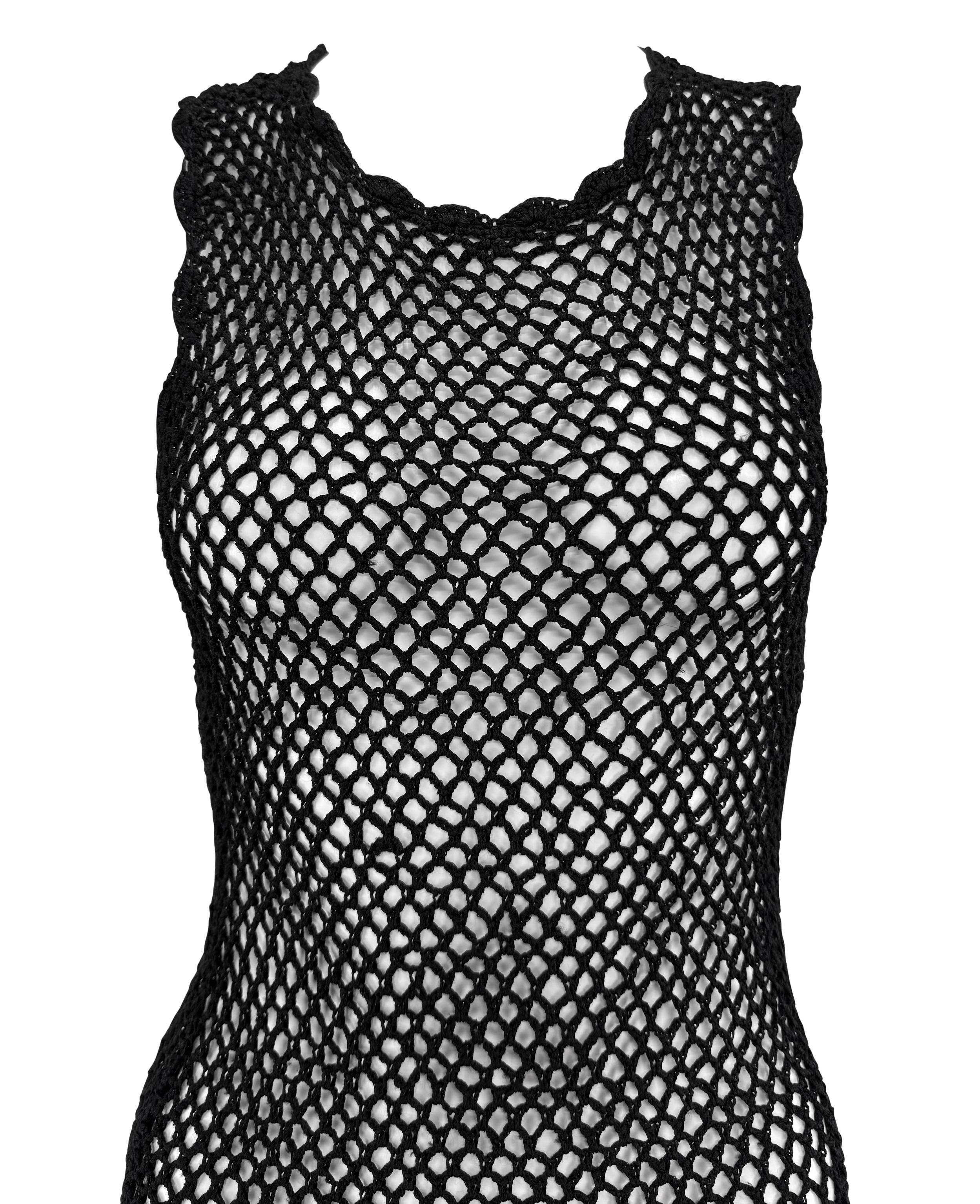 Este minivestido de Dolce & Gabbana de finales de los 90 está confeccionado en punto de ganchillo negro, creando una silueta de malla transparente que abraza el cuerpo. El diseño se completa con bordes festoneados en el escote y el dobladillo.