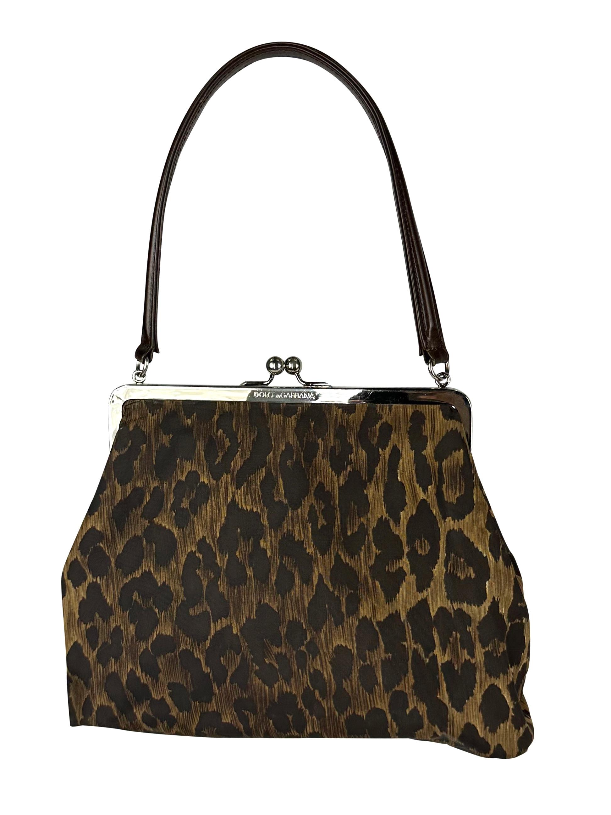 Presenting an incredible leopard print Dolce and Gabbana kiss lock bag. From the late 1990s, this nylon bag features a cheetah print throughout and is made complete with a silverplate logo clam closure.

Approximate Measurements: 
Handle Drop: