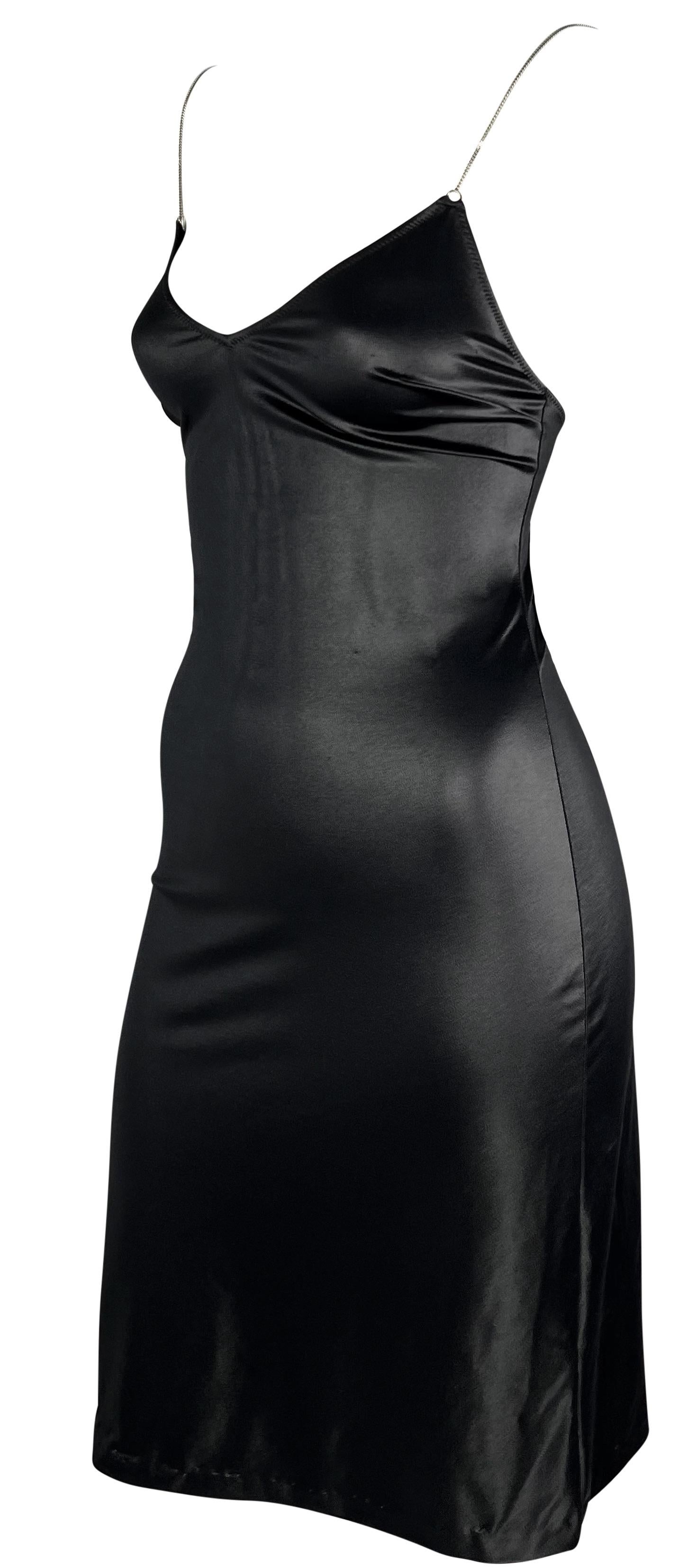 Este minivestido negro brillante de Dolce & Gabbana se ciñe perfectamente al cuerpo. Este vestido estilo slip de efecto mojado de los años 90 tiene escote y espalda bajos. El vestido se completa con finos tirantes de cadena plateada. 

Medidas