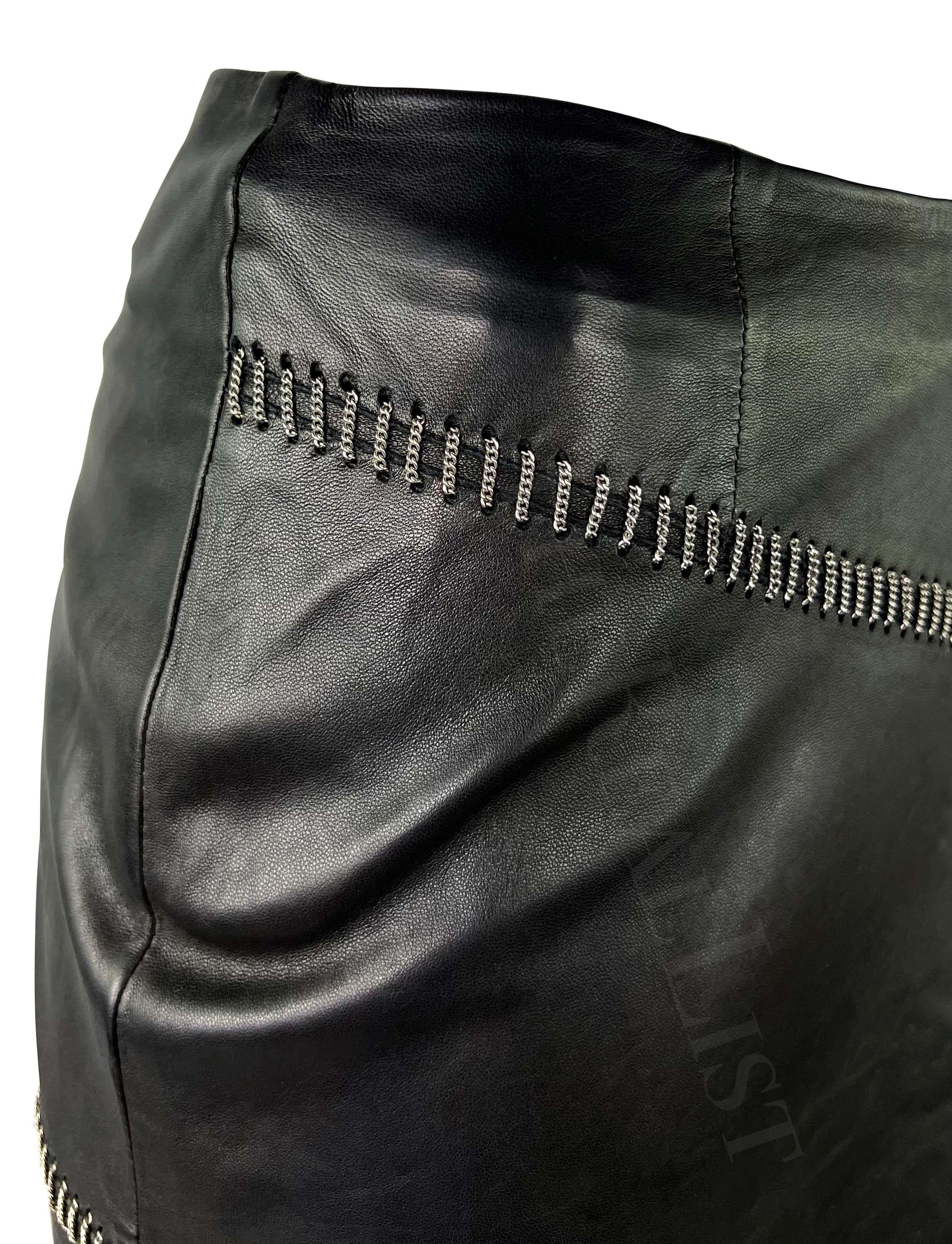 Presenting a fabulous black leather Gianni Versace pencil skirt, designed by Donatella Versace. From the Spring/Summer 1999 collection, this skirt is constructed entirely of leather and is complete with a woven asymmetrical silver-tone chain accent.