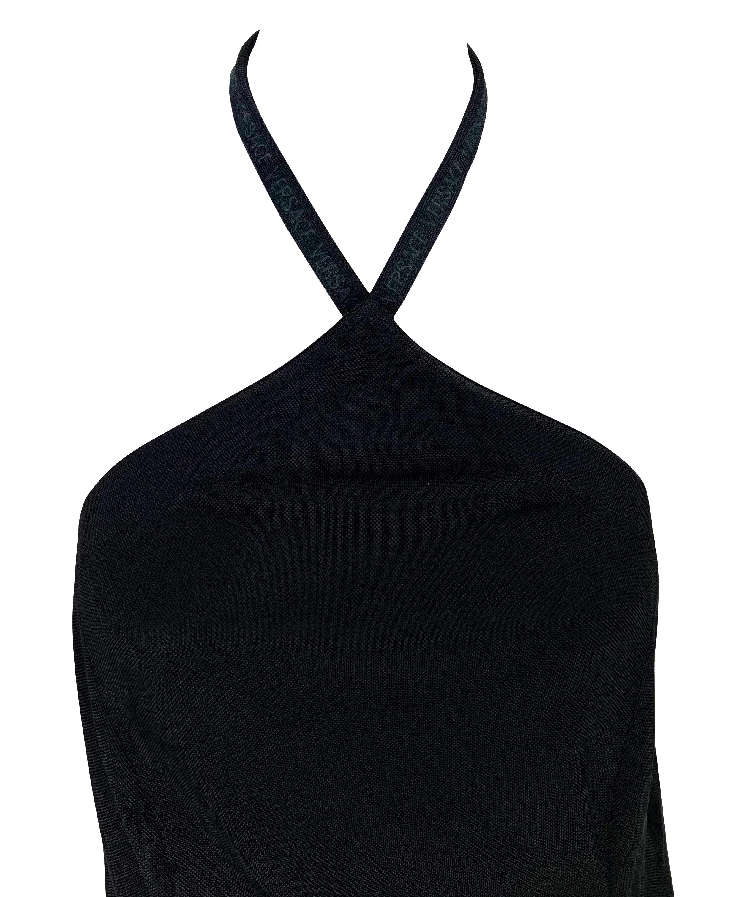 Nous vous présentons une magnifique robe Gianni Versace en maille noire à dos nu, dessinée par Donatella Versace. Datant de la fin des années 1990, cette robe tube en maille noire est suspendue à la nuque. La robe est complétée par l'inscription 