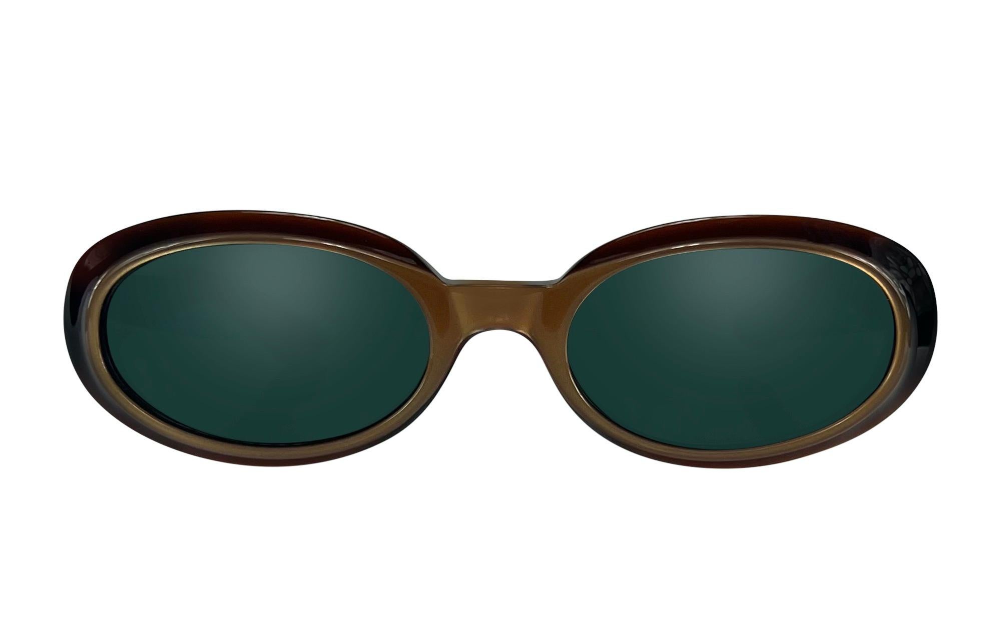 These late 1990s Gucci by Tom Ford sunglasses feature an oval shape with a bronze-accented acrylic front and gold-tone 'G' logo on the temples. The tortoiseshell frame is paired with tinted lenses for a classic look.

Approximate measurements: