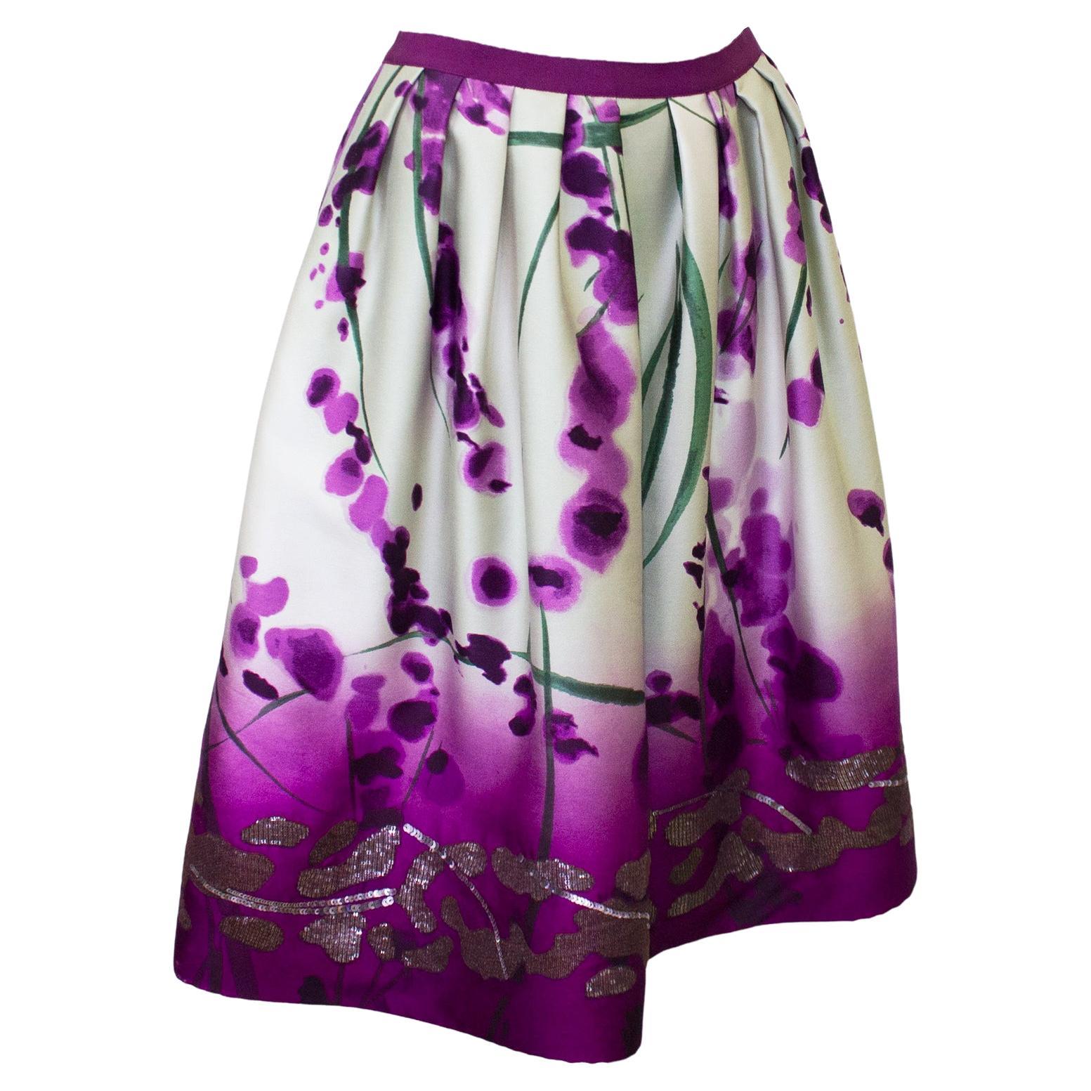 Late 90s Oscar de la Renta silk blend skirt featuring a beautiful watercolor printed purple floral pattern and finished with a sequin adorned hem. The skirt goes from light to dark at the hem and flares out from the waist. In excellent condition,