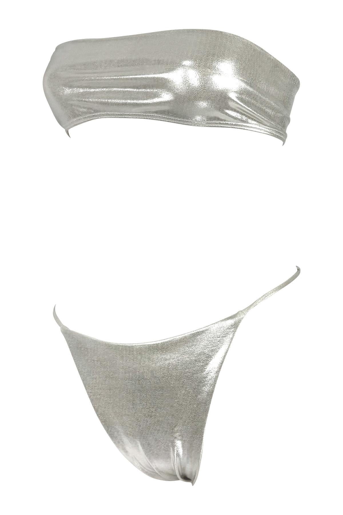 Este conjunto de bikini de Richard Tyler de finales de los 90 presenta un top bandeau sin tirantes y unas braguitas de talle alto en un tejido metálico plateado reflectante. La silueta minimalista se realza con un elegante acabado de alto brillo y