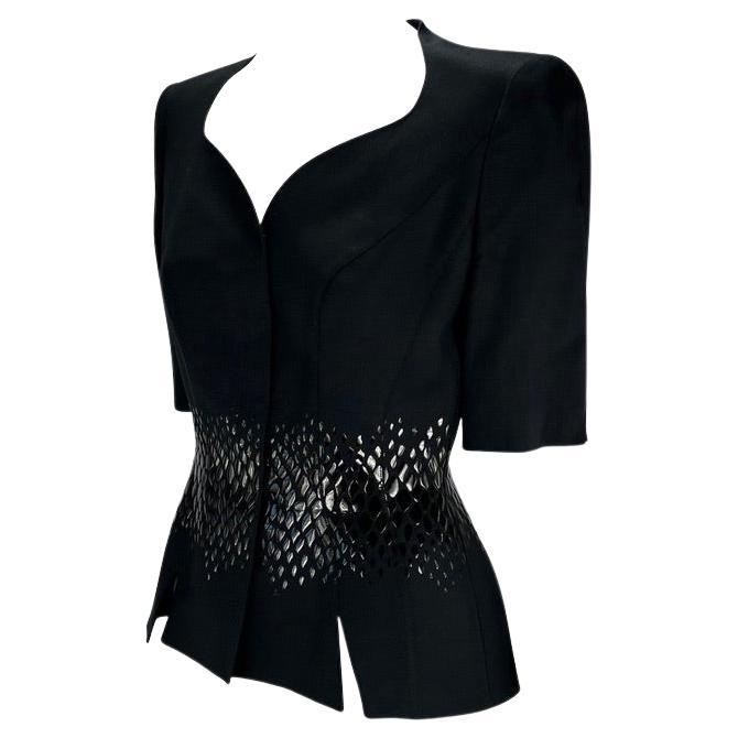 Presenting a short sleeve black Thierry Mugler blazer, designed by Manfred Thierry Mugler. This blazer from the 2000 Cruise collection features a sweetheart neckline, vents at the front, built-in shoulder pads, and a scale appliqué. The shiny scale