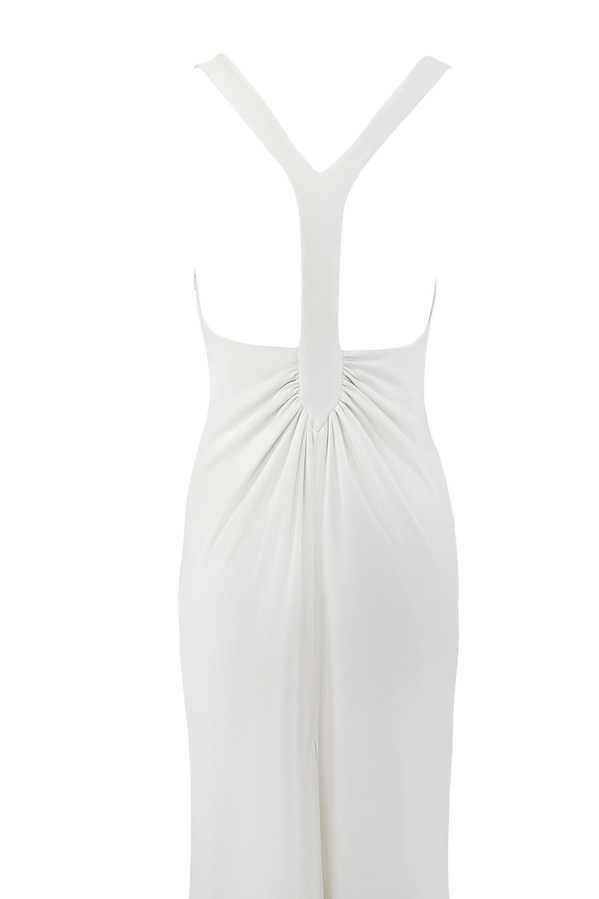 Cette robe blanche, créée par Valentino Garavani à la fin des années 1990, présente un corsage ajusté sans manches, un décolleté plongeant et un dos ouvert spectaculaire avec une bretelle en Y froncée. Coupe fluide de la silhouette pleine longueur.