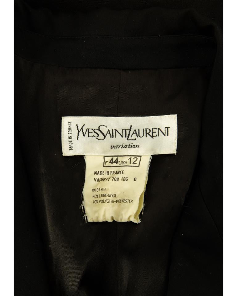 A late 1990’s Yves Saint Laurent Variation elongated black wool gabardine fitted smoking coat with black silk satin detail throughout, the front V-neckline with small collar and large angular and curved revers, the two-piece set-in sleeves with faux