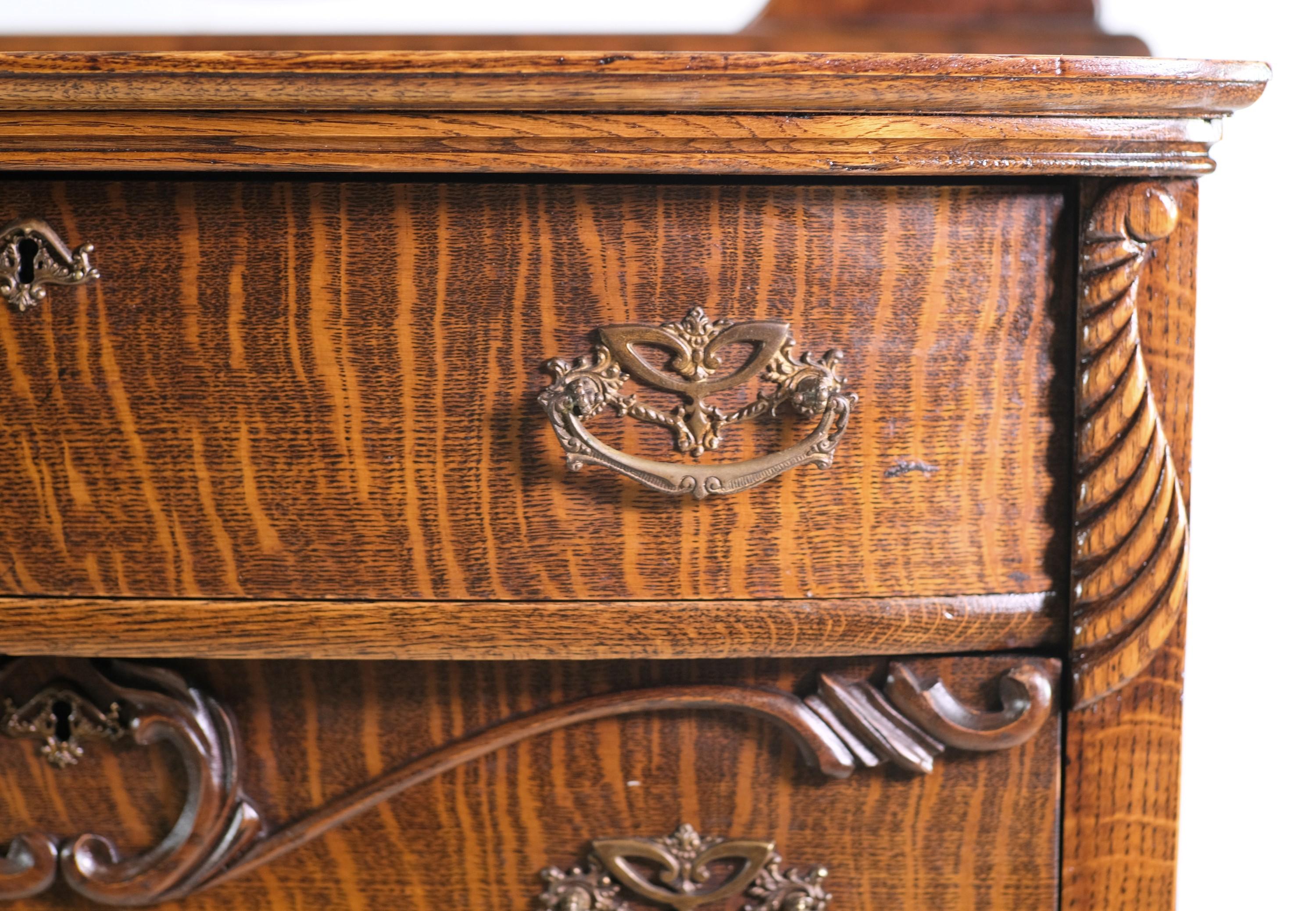 Late 19th century tiger oak highboy dresser featuring five dovetailed drawers and hand carved details. Mounted on top is the original oval adjustable mirror. Retrieved from a Northeastern Pennsylvania residence. This has been carefully restored and