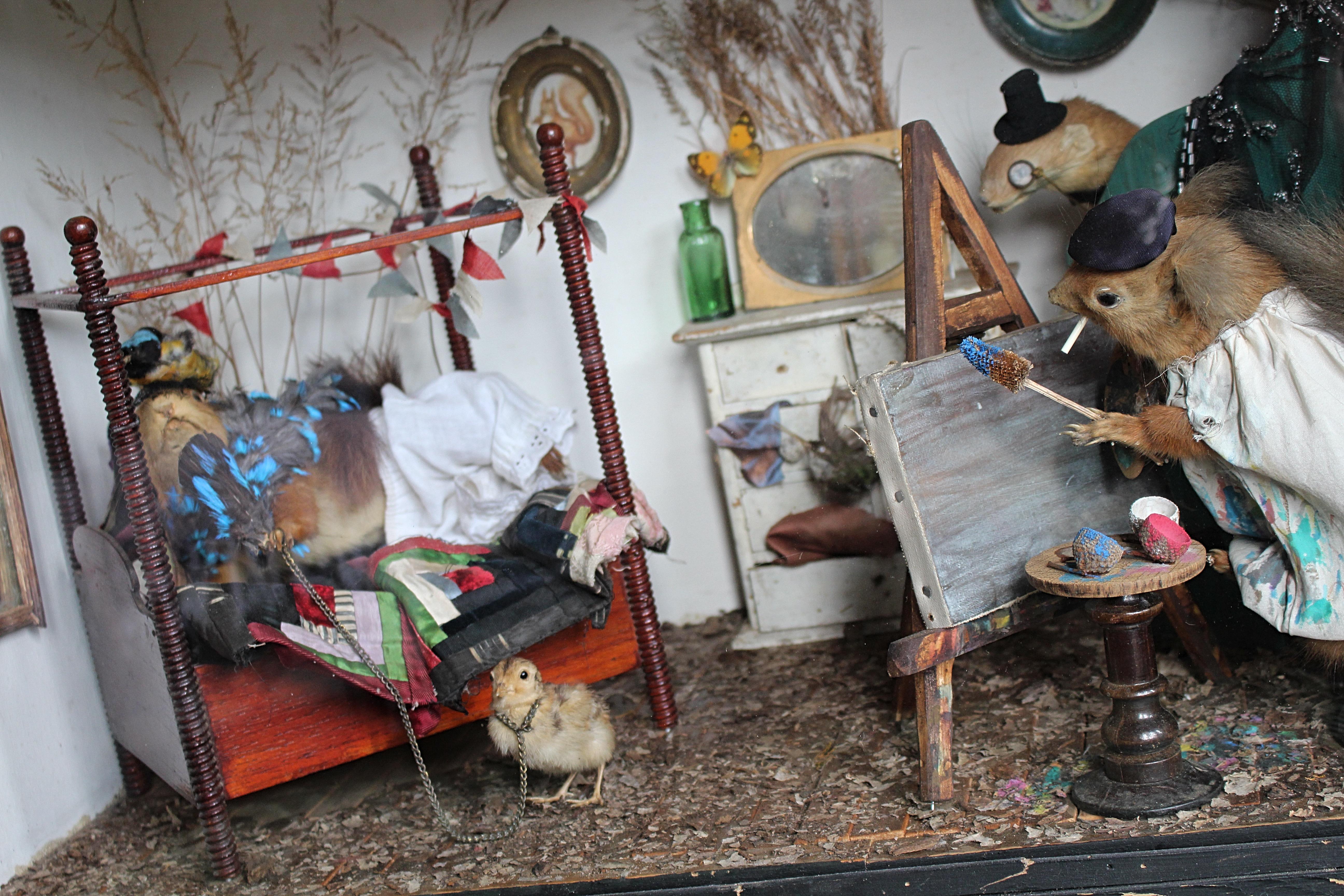 Fin du 19e siècle, scène taxidermique anthropomorphique en coffret représentant deux écureuils et un bouc dans un décor de chambre à coucher/boudoir. Un écureuil habillé en artiste avec un béret, une blouse de peintre fumant une cigarette avec son