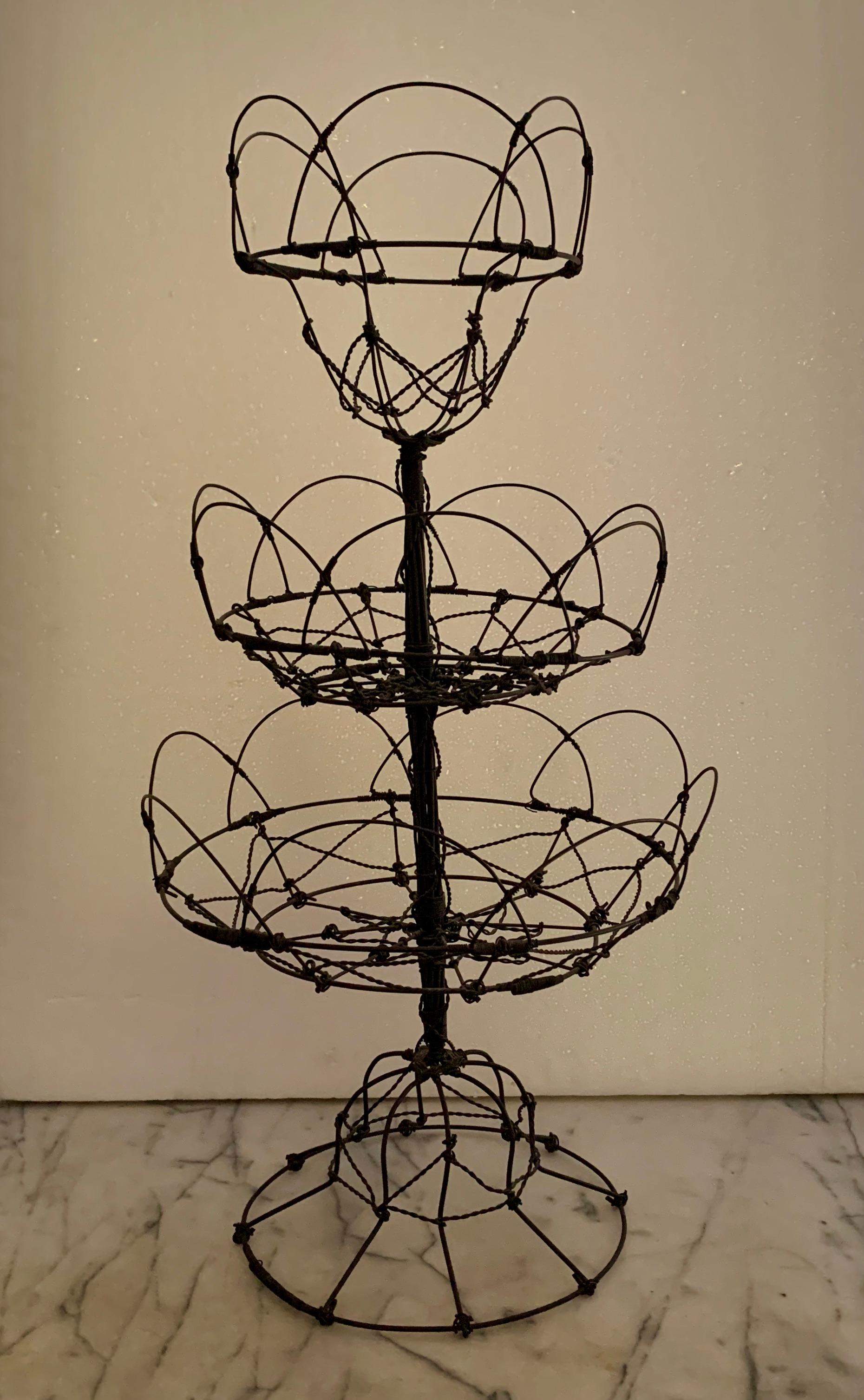 From France, circa 1890-1910, a triple-tiered, twisted wire standing basket, two and a half feet tall!

The most incredible one I’ve handled – amazing as a table-center, shop display, or on a kitchen countertop used as originally intended