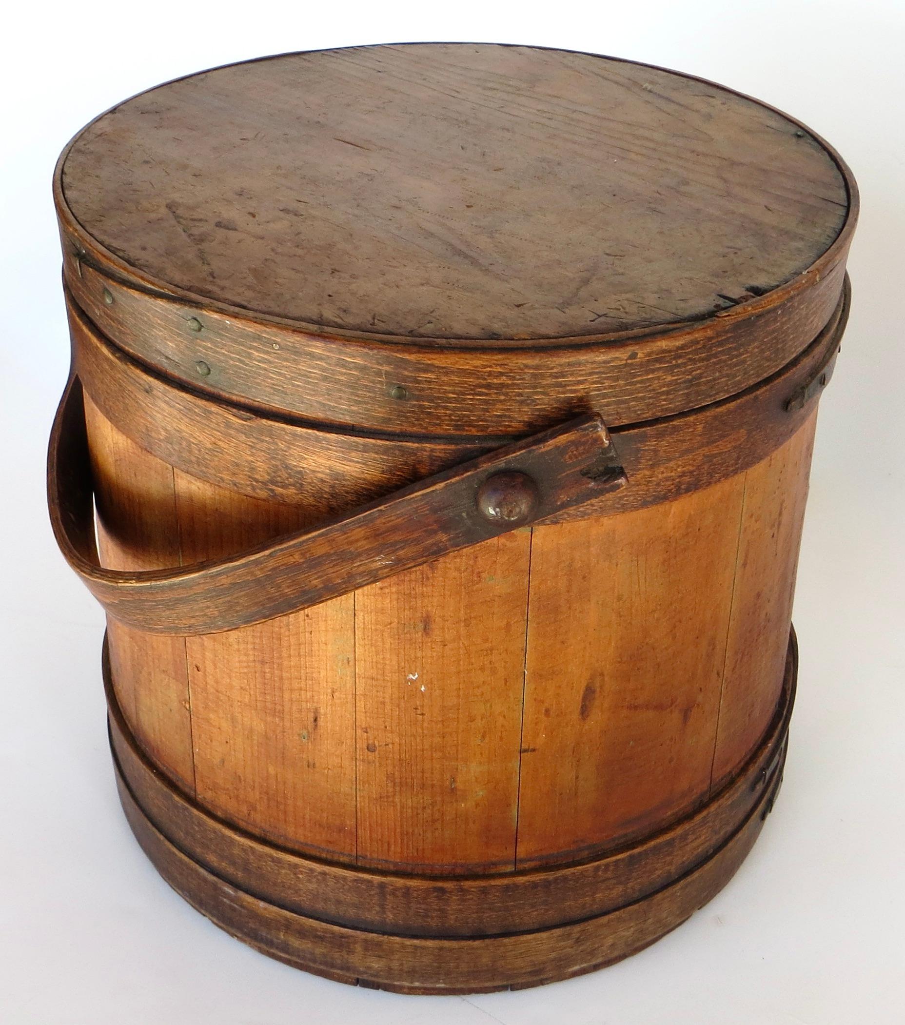 This is an authentic and late 19th century hand made wooden Shaker bucket from Pennsylvania. in all original and unrestored, very good condition; with it's original lid and lovely patinated surface. It maintains a bentwood broad 1  1/4