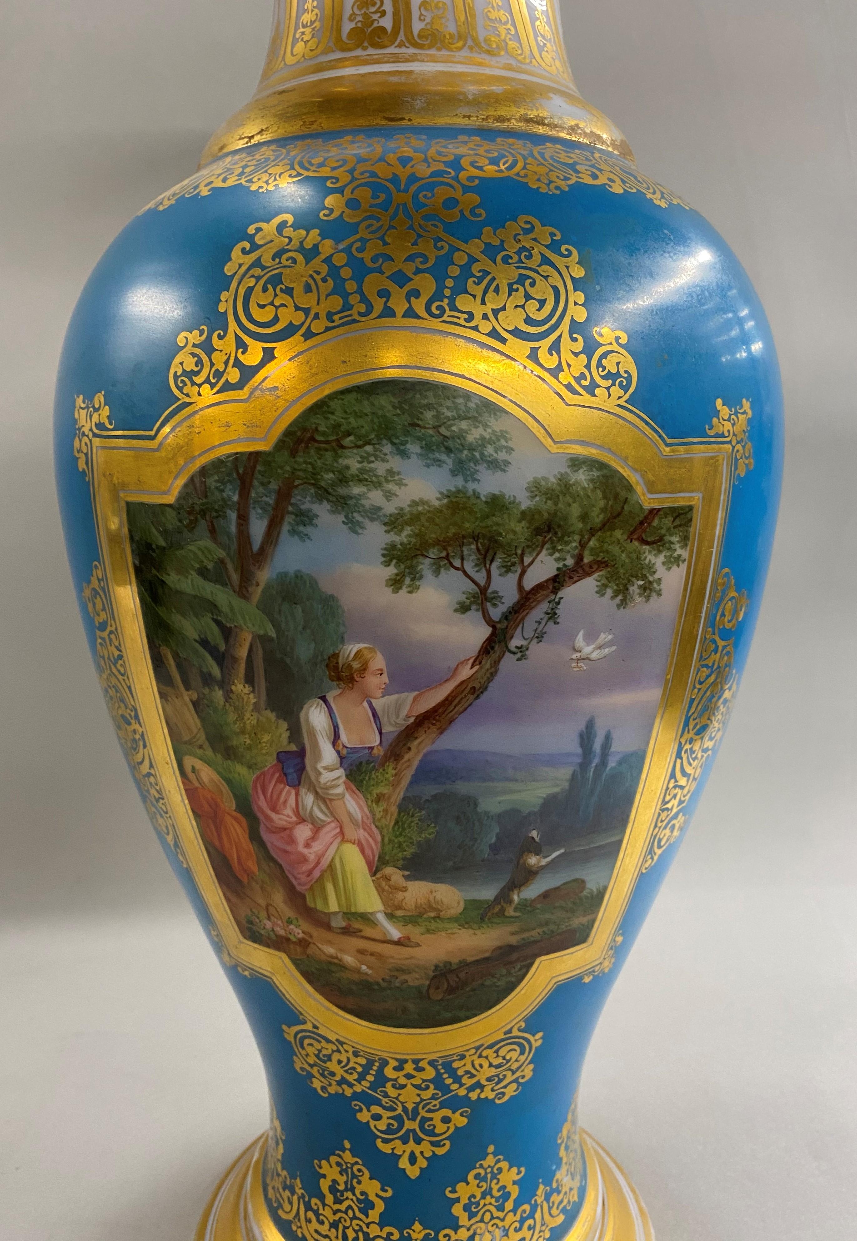 A beautiful palace size French Baccarat opaline glass baluster form vase, circa 1880, with fine hand painted genre and foliate panels in white opal crystal with polychrome enamels on a blue background, unsigned, with gilt swirl highlights on the rim