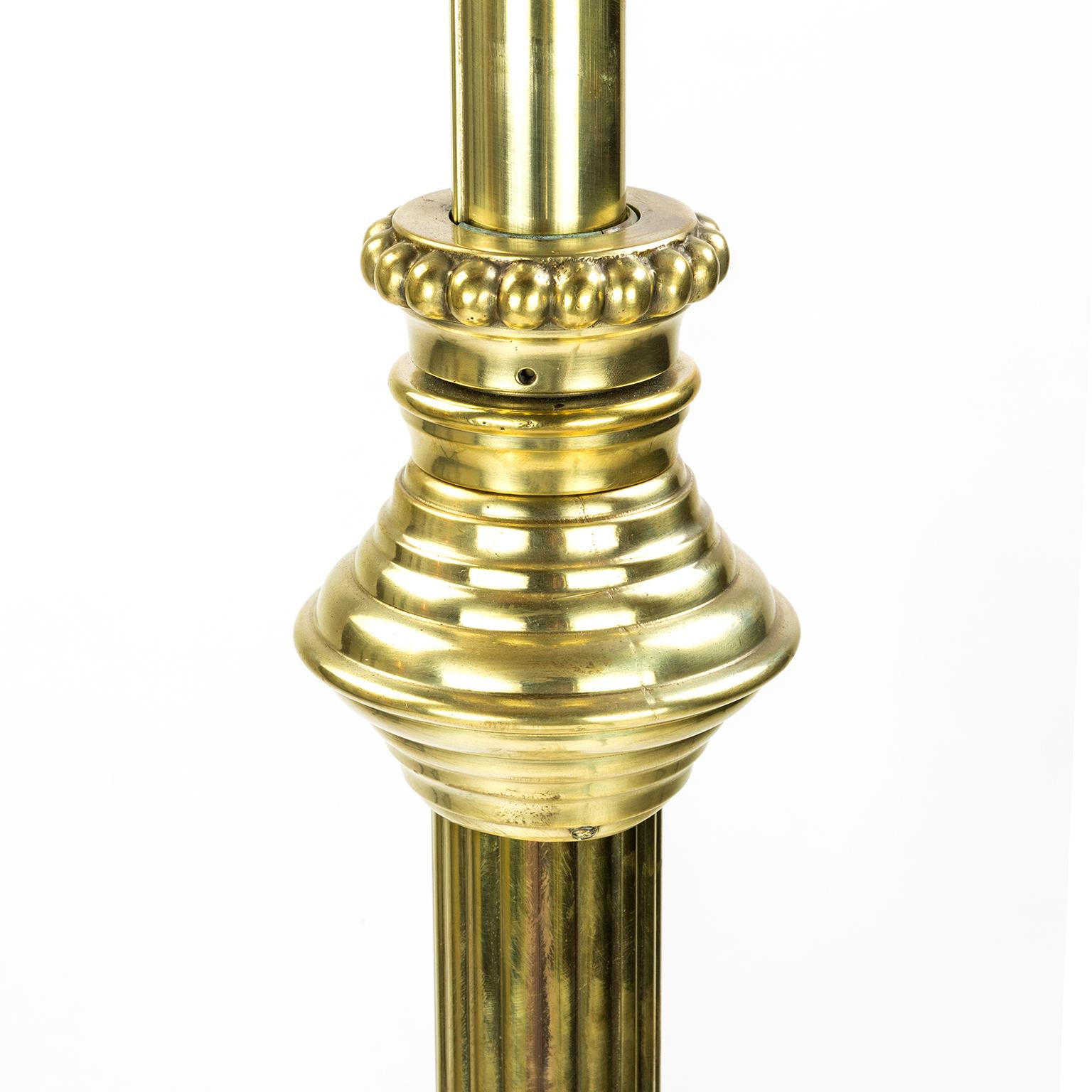 A telescopic brass standard lamp dating from about 1890, the base is weighted, and the illumination coming from three individually switched heads each with frosted glass shade.