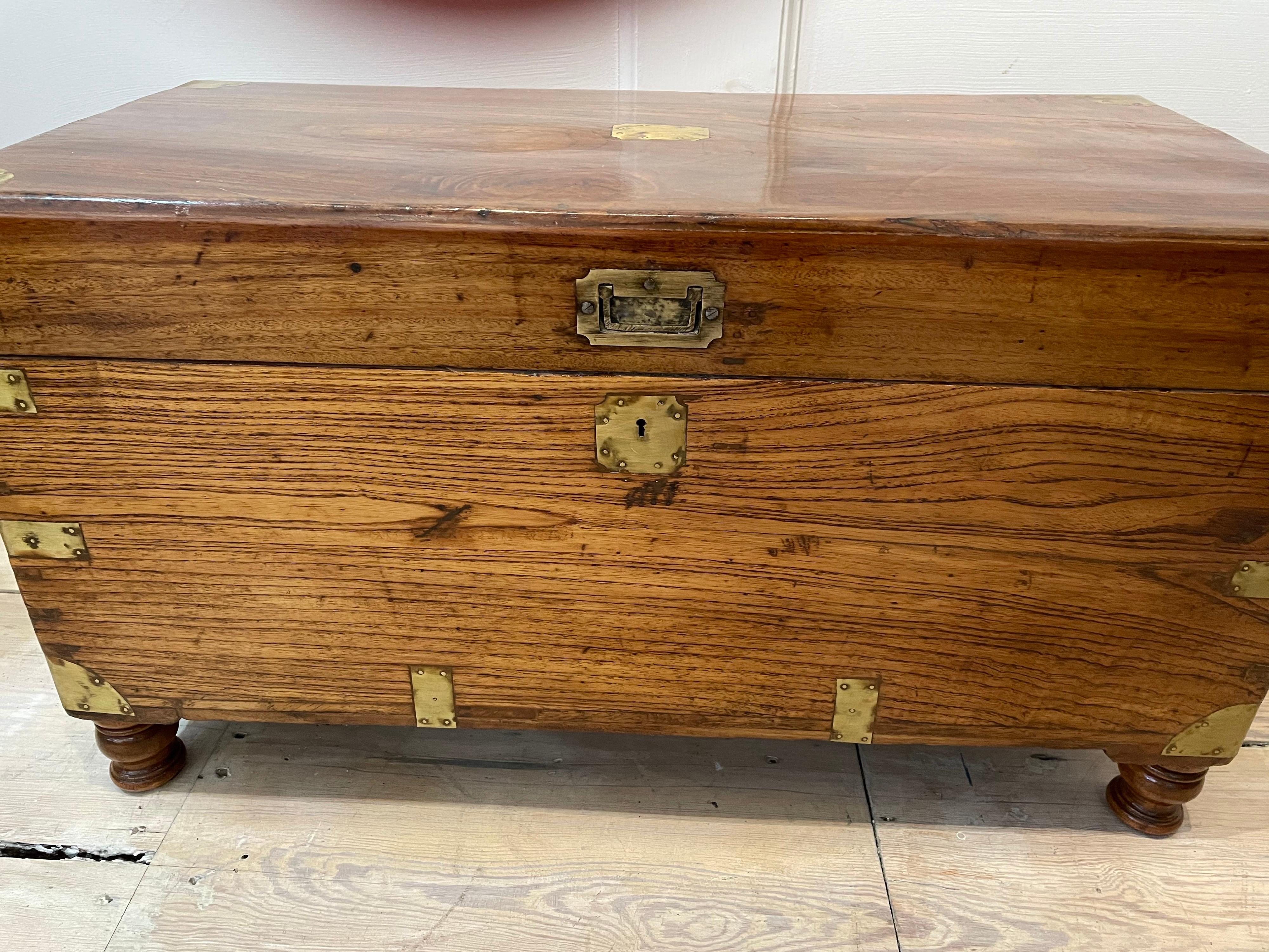A classic British Campaign camphor wood sea chest with brass strap corners and brass handles, dovetail joins, from the late 19th century, refinished. Working lock (replaced) and key with added turned feet making for a better use as a coffee table