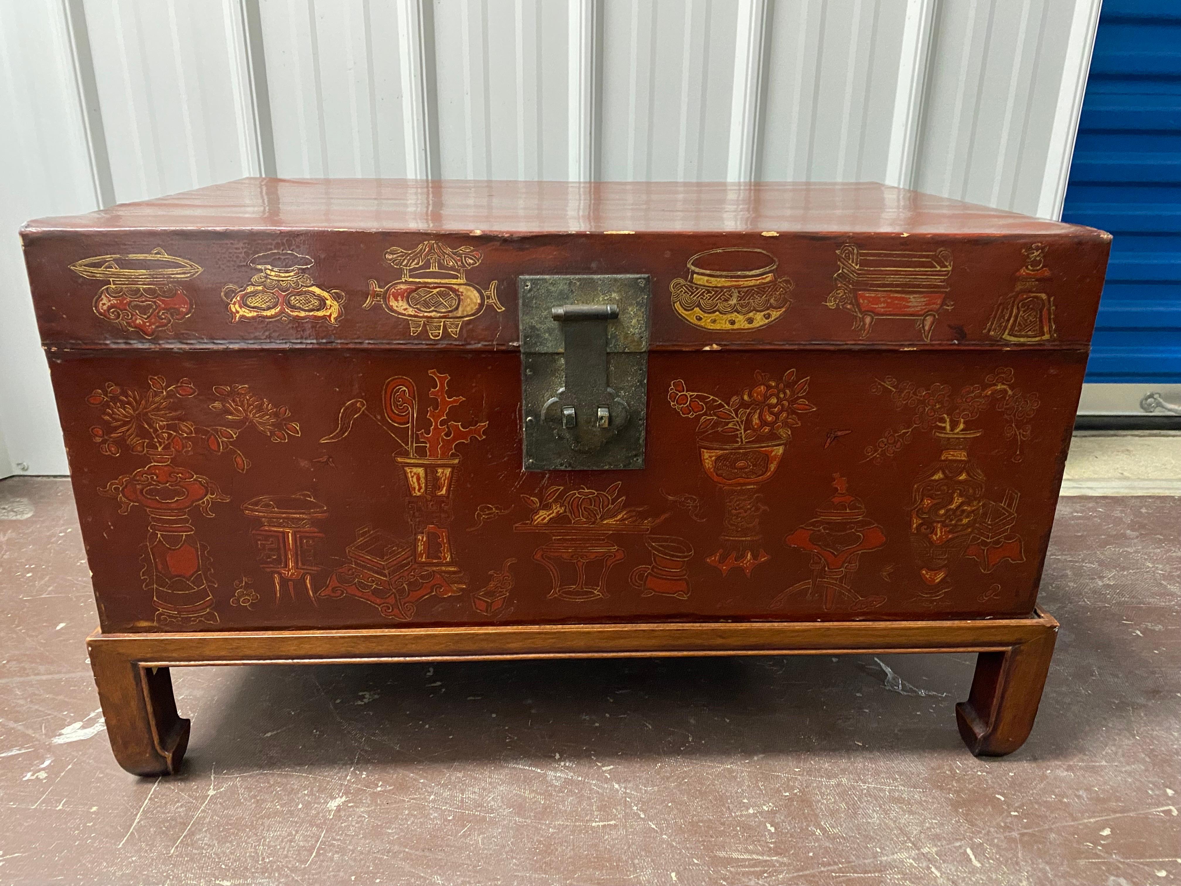 Late 19th Century Chinese Export Painted Leather Chest on Later Stand.  Deep red paint on leather wrapped wood trunk/chest. The front is adorned in beautiful gold painted Chinese vessels, some with flowers. The sides are more simple gold painted