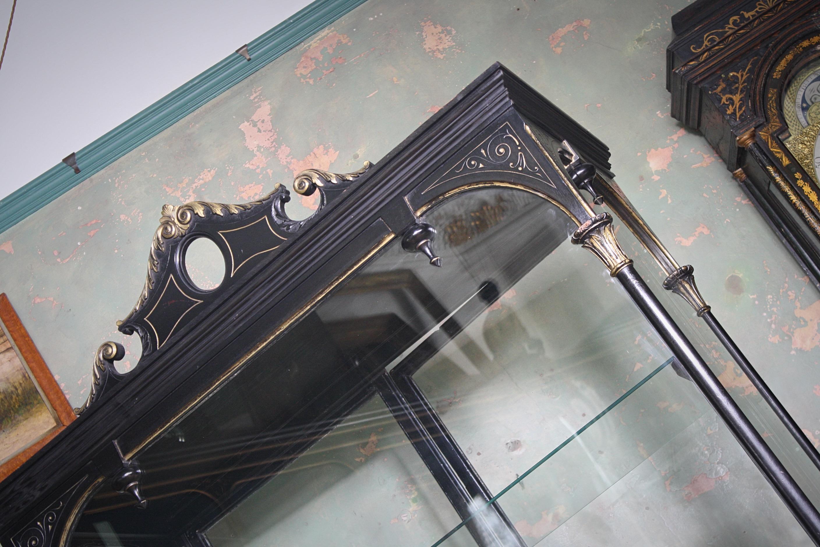 A large fully glazed shop display cabinet, ebonized hardwood with gilt highlights/decoration, late 19th century.

Adjustable bronze internal shelving, velvet covered base.

Manufactured by Frederick Sage & Co shop fitters of London, started in