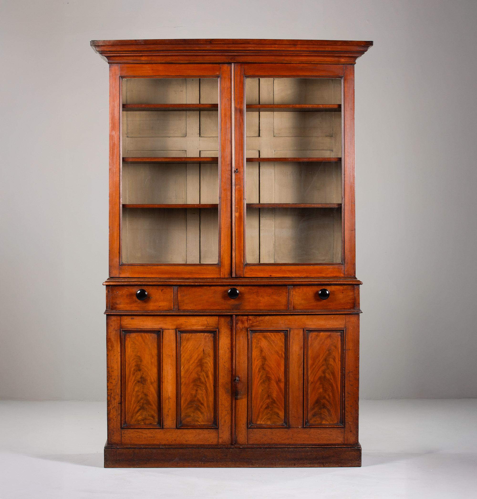 Found in England, this mahogany cupboard dates from the 1870s. Cabinet has locking glazed doors on the top with three adjustable shelves on each side. Three functional drawers and locking lower storage compartment has single interior shelf. Unknown