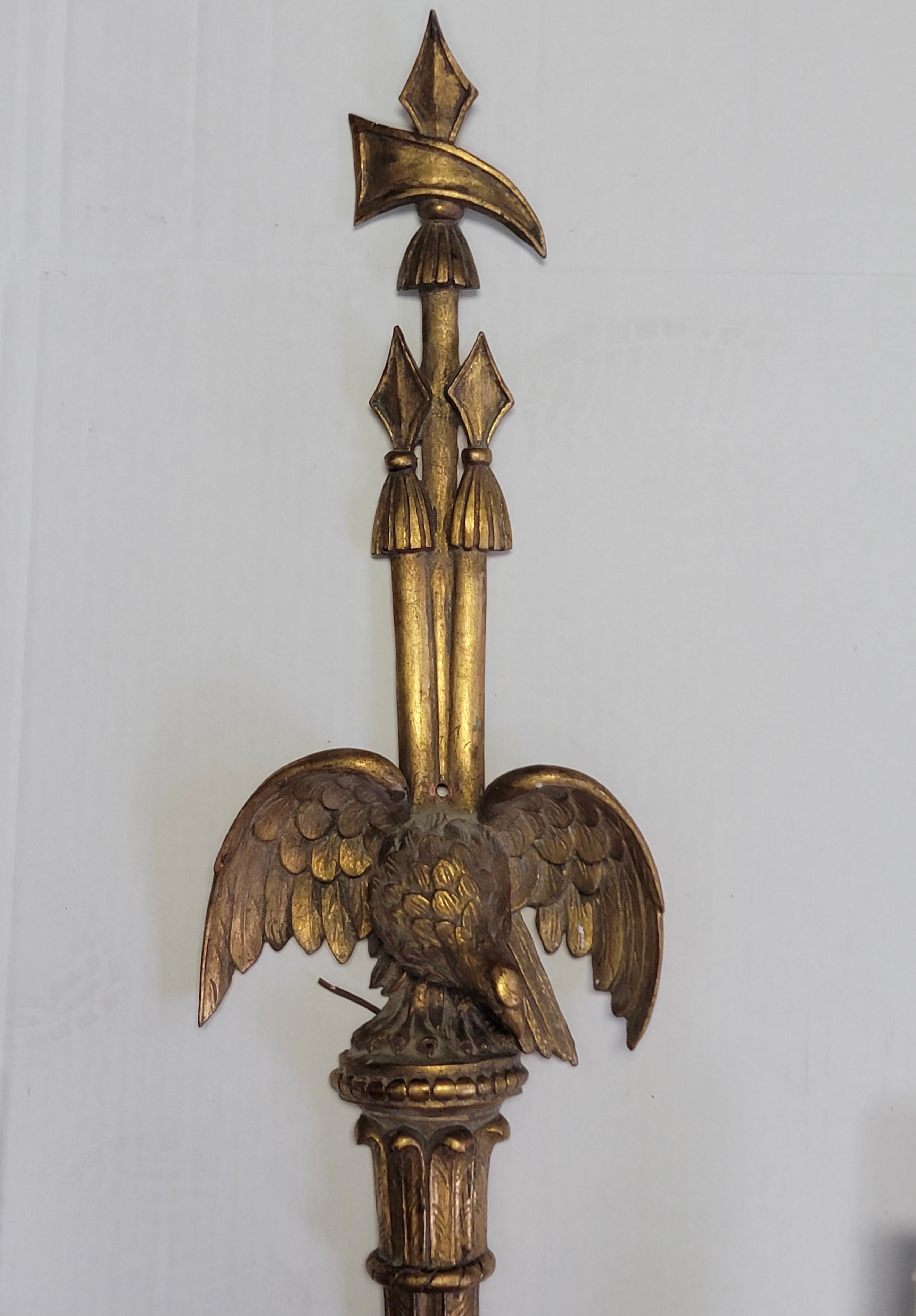These have a timeless elegance. It is a large scale pair of carved giltwood sconces with Federal styling. The facing eagles are adorned with axes and arrows. The wiring and candle covers are new. They most likely date to the later part of the 20th