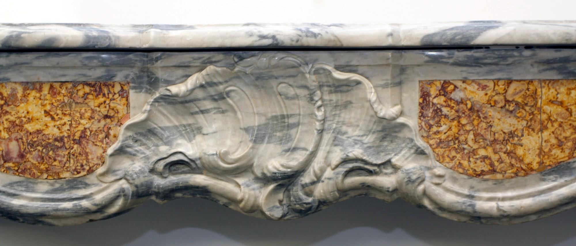 Late 19th century hand carved French Louis XV style marble mantel. Features a pompadour motif and inlaid breche with gray marble. Please note, this item is located in our Scranton, PA location.