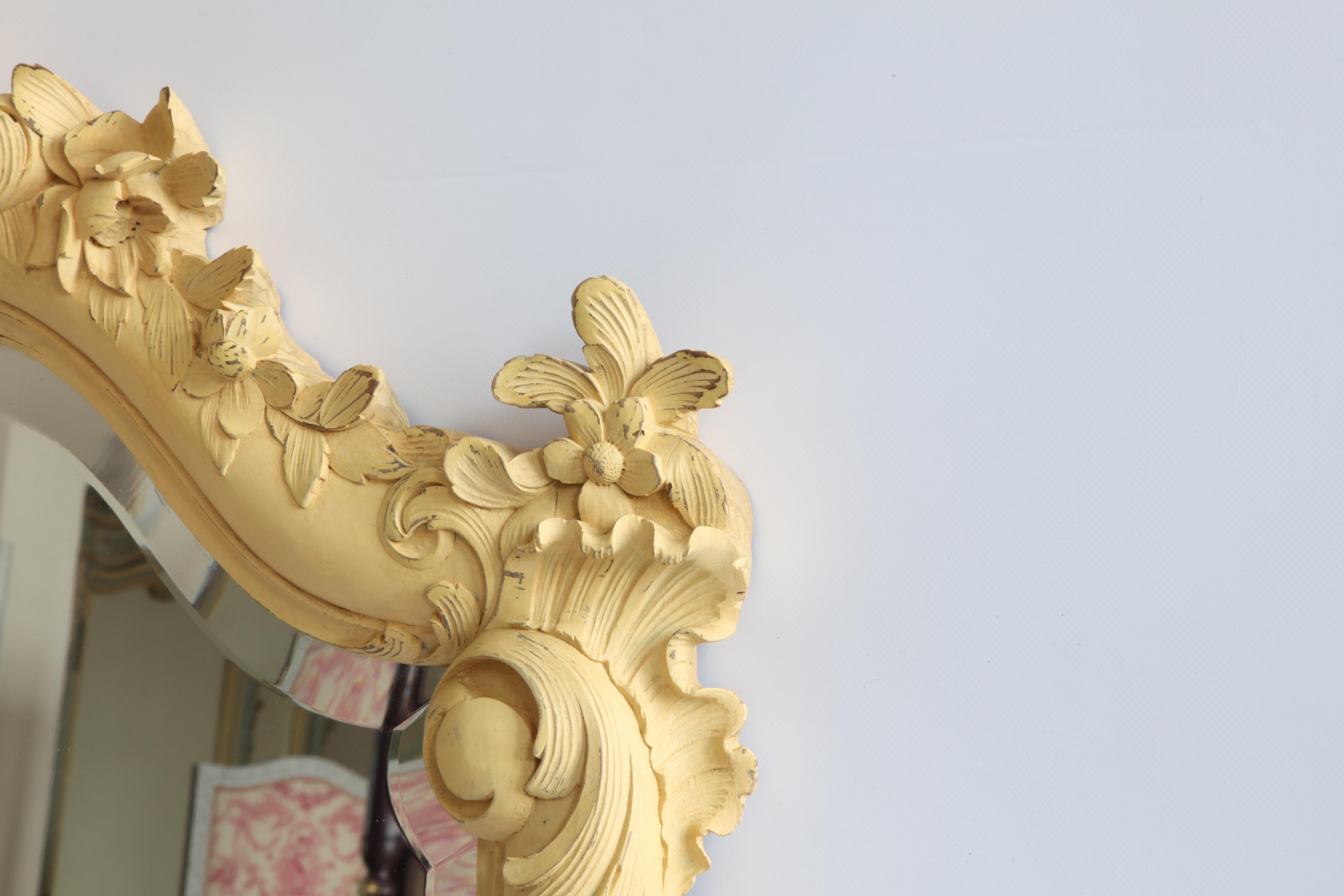Ein französischer Rocaille-Spiegel des späten 19. Jahrhunderts. Handgeschnitzt aus Massivholz und in einem sonnigen provenzalischen Gelb gehalten. Der Spiegel ist rundherum abgeschrägt.
 
