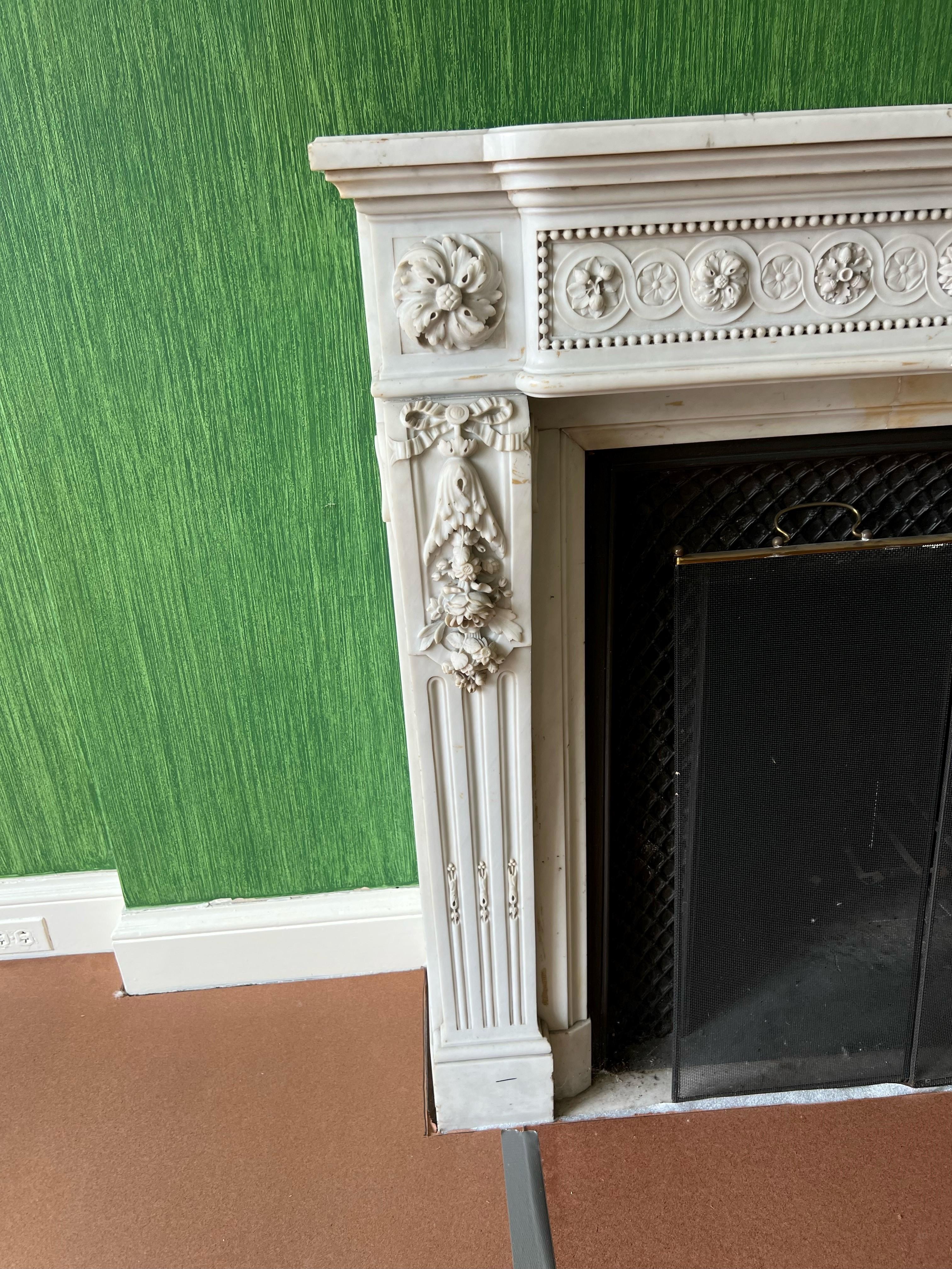 Late 19th c. Louis XVI style mantel in carrara marble with stepped frieze elaborated with guilloche carving detail, stop fluted tablet and rose swag. Fluted console jambs exhibit ribbon and rose carving details and support corner blocks with