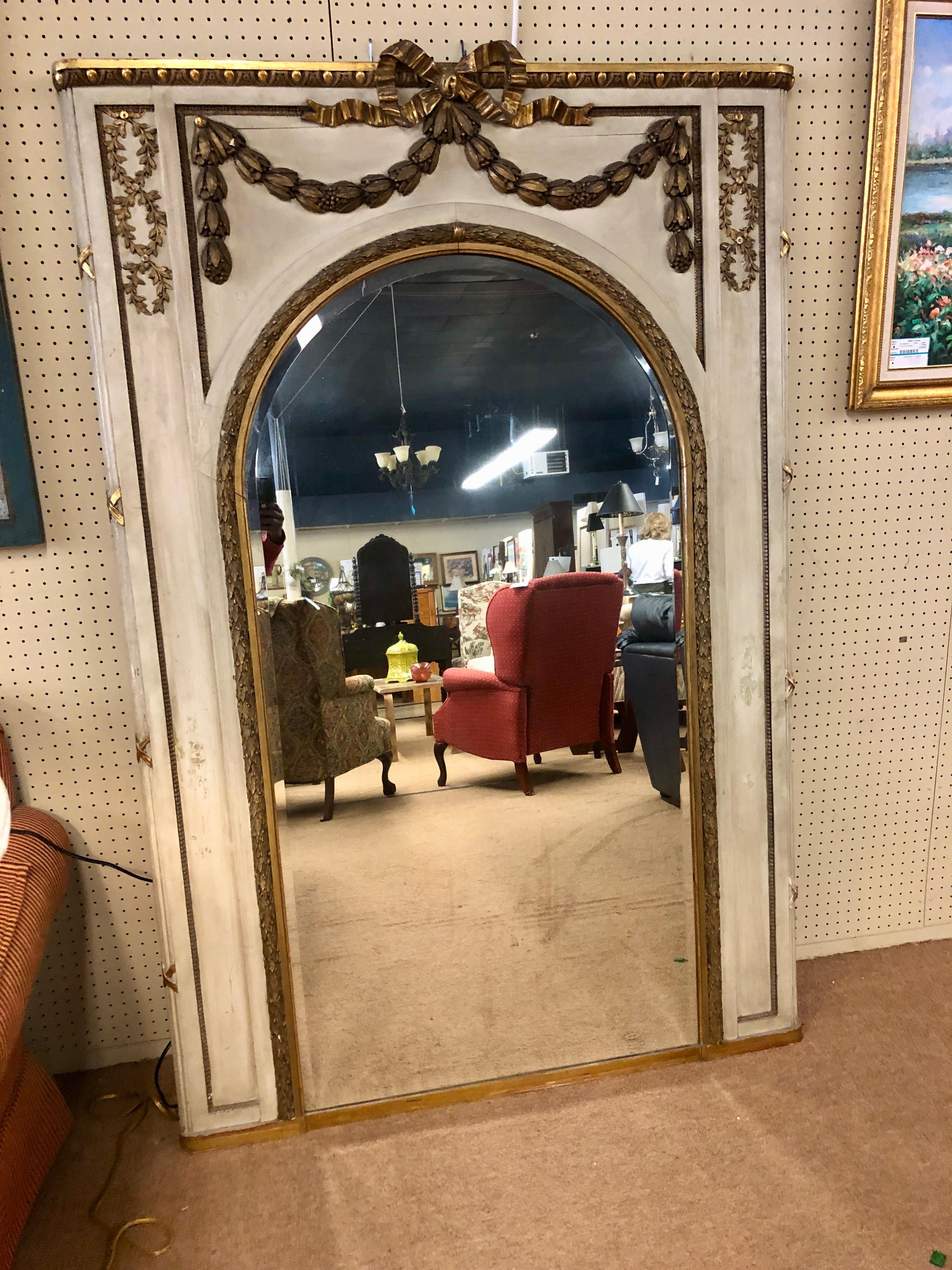  A beautiful French Louis XV style painted and gilt decorated mirror. The frame  features an arched mirror plate trimmed with gilt gesso decoration. The top with draped and bow decoration. Mirror is in good condition with some missing moldings at