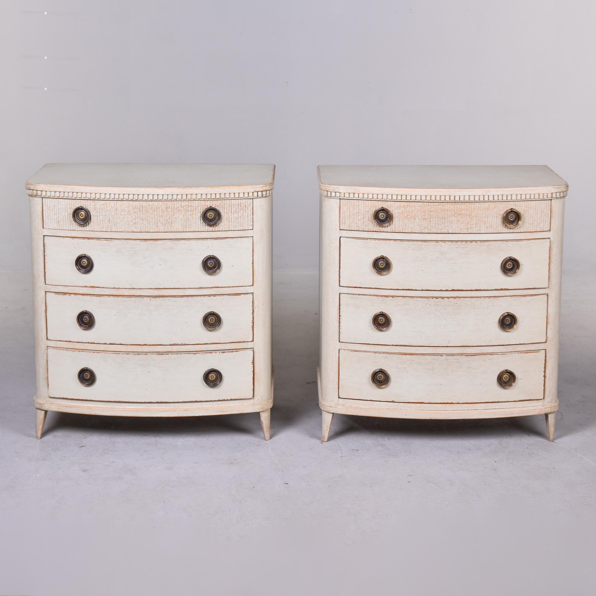 Pair of Swedish four drawer chests with antique white painted finish. Details include top drawers with reeded fronts, dental trim around top edge, tapered and angled front legs and brass ring-pull hardware. Unknown maker. Versatile size and function