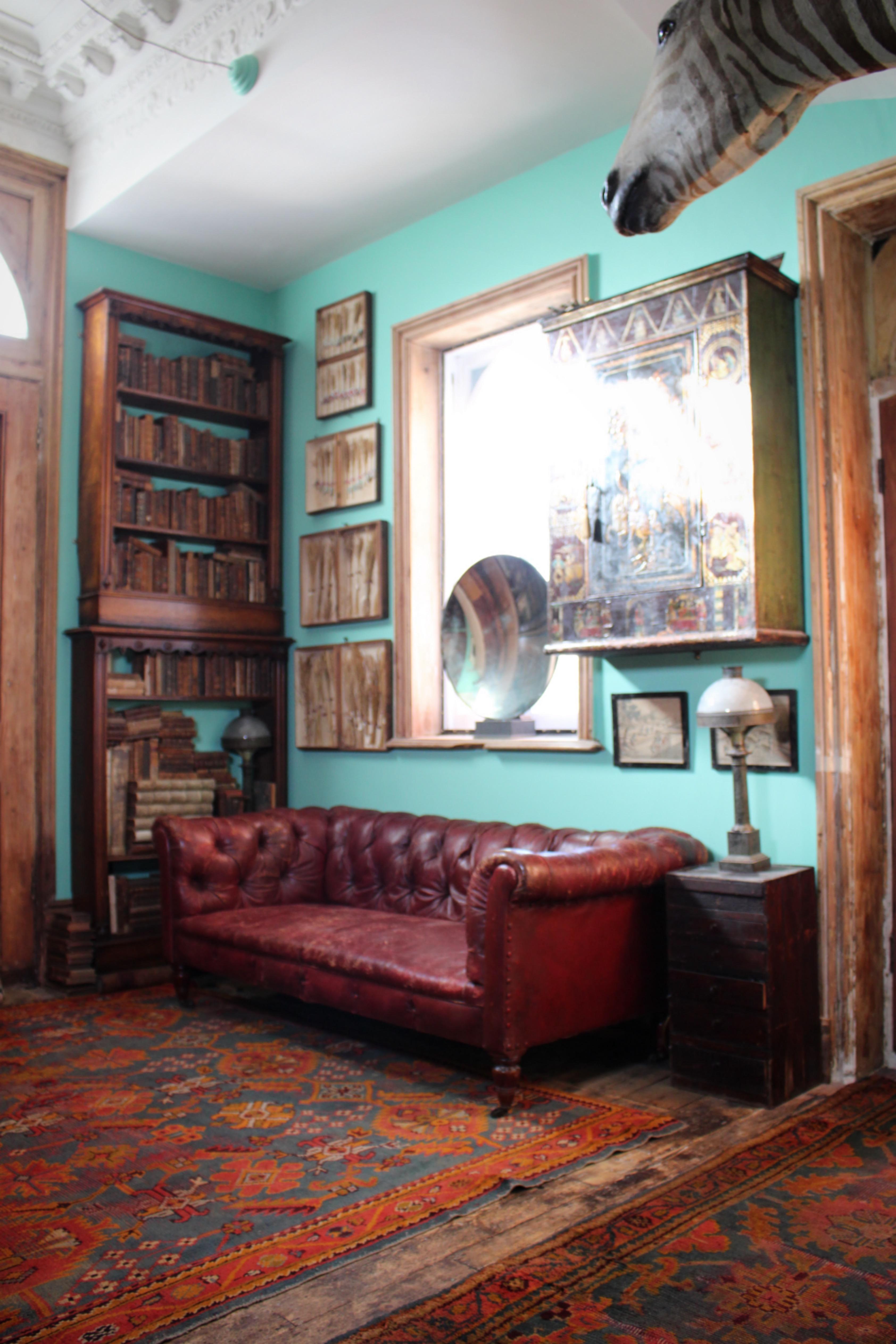 A fine red deep buttoned moroccan leather upholstered chesterfield settee,  raised on short turned lignum vitae legs with brass cup castors.

The leather in perfectly worn country house condition, the upholstery is in particularly good condition.