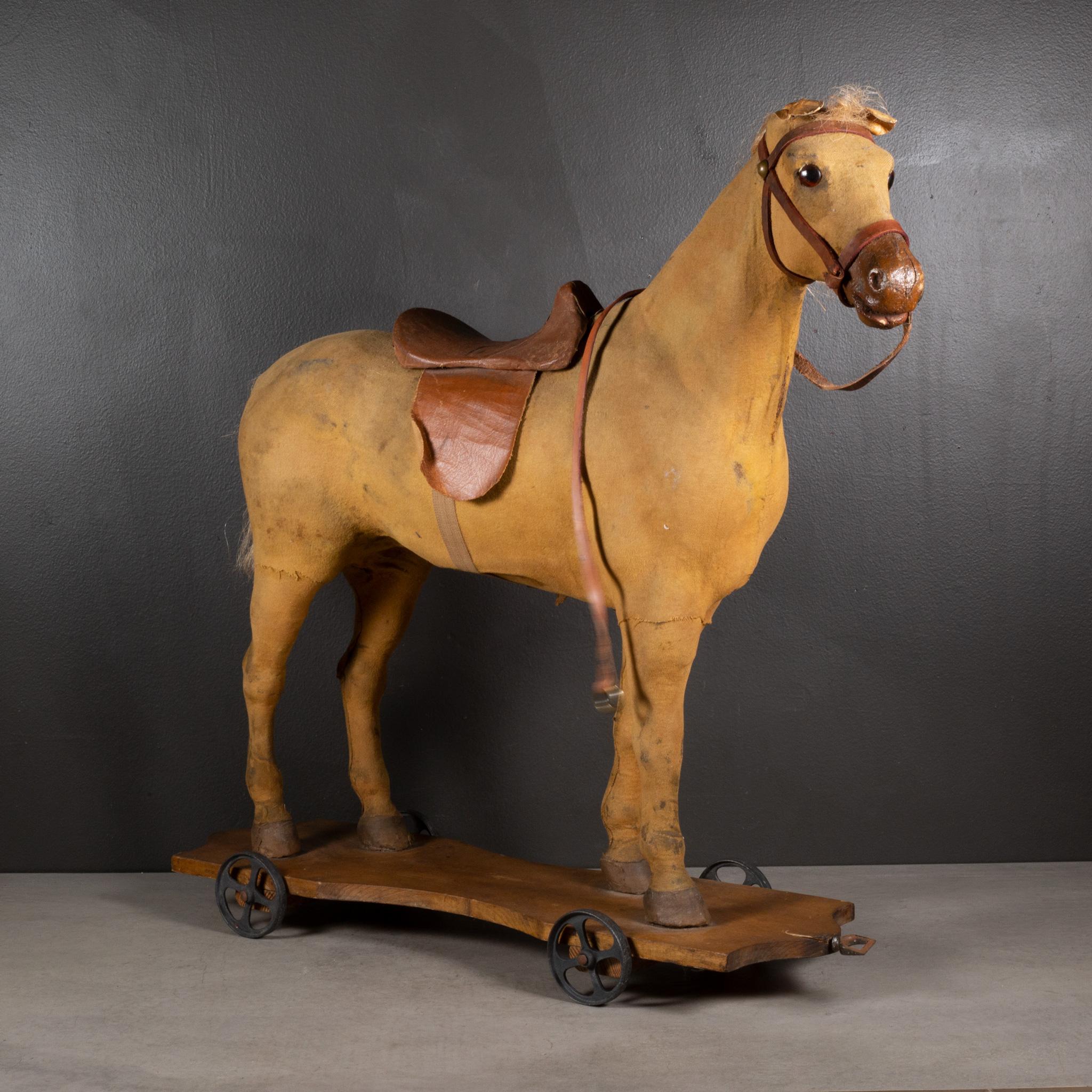 ABOUT

An early 20th century carved wooden horse pull-toy covered in fabric with glass eyes, leatherette ears, leather saddle and halter, human hair tail and mane mounted on a shaped wooden platform with steel wheels. Brass rings on the reins and