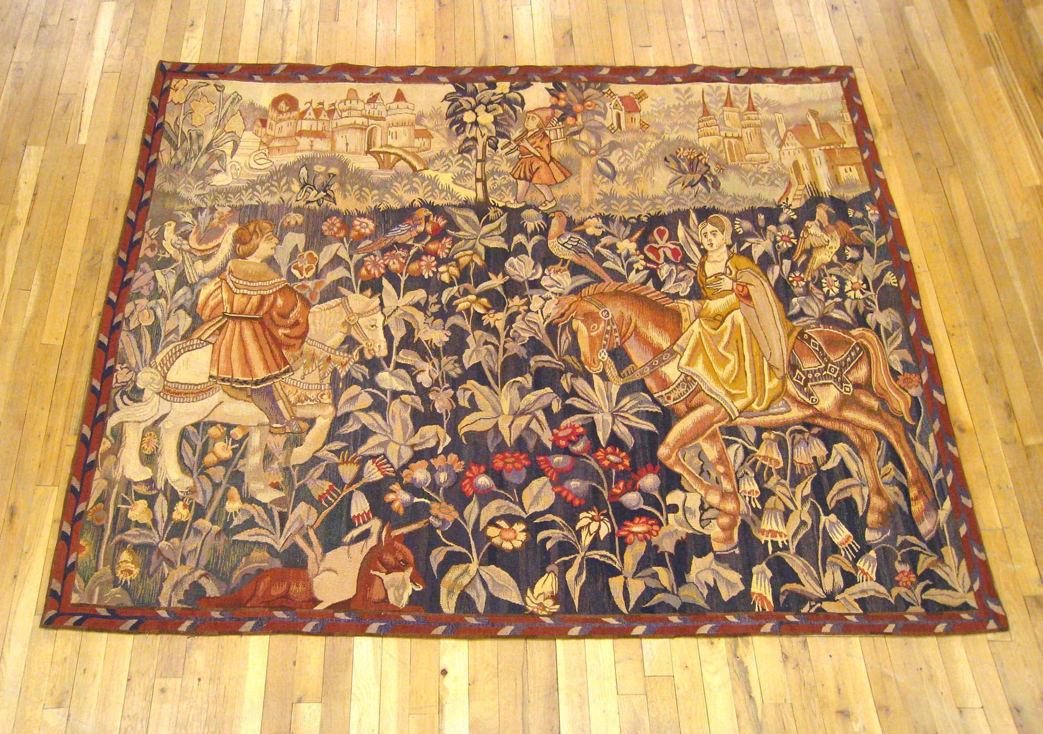 A French tapestry from the end of the 19th century or the turn of the century, presenting an aristocratic hunting scene in a mille fleurs setting, with a nobleman and a noblewoman astride horses at left and right, respectively, a hound with its