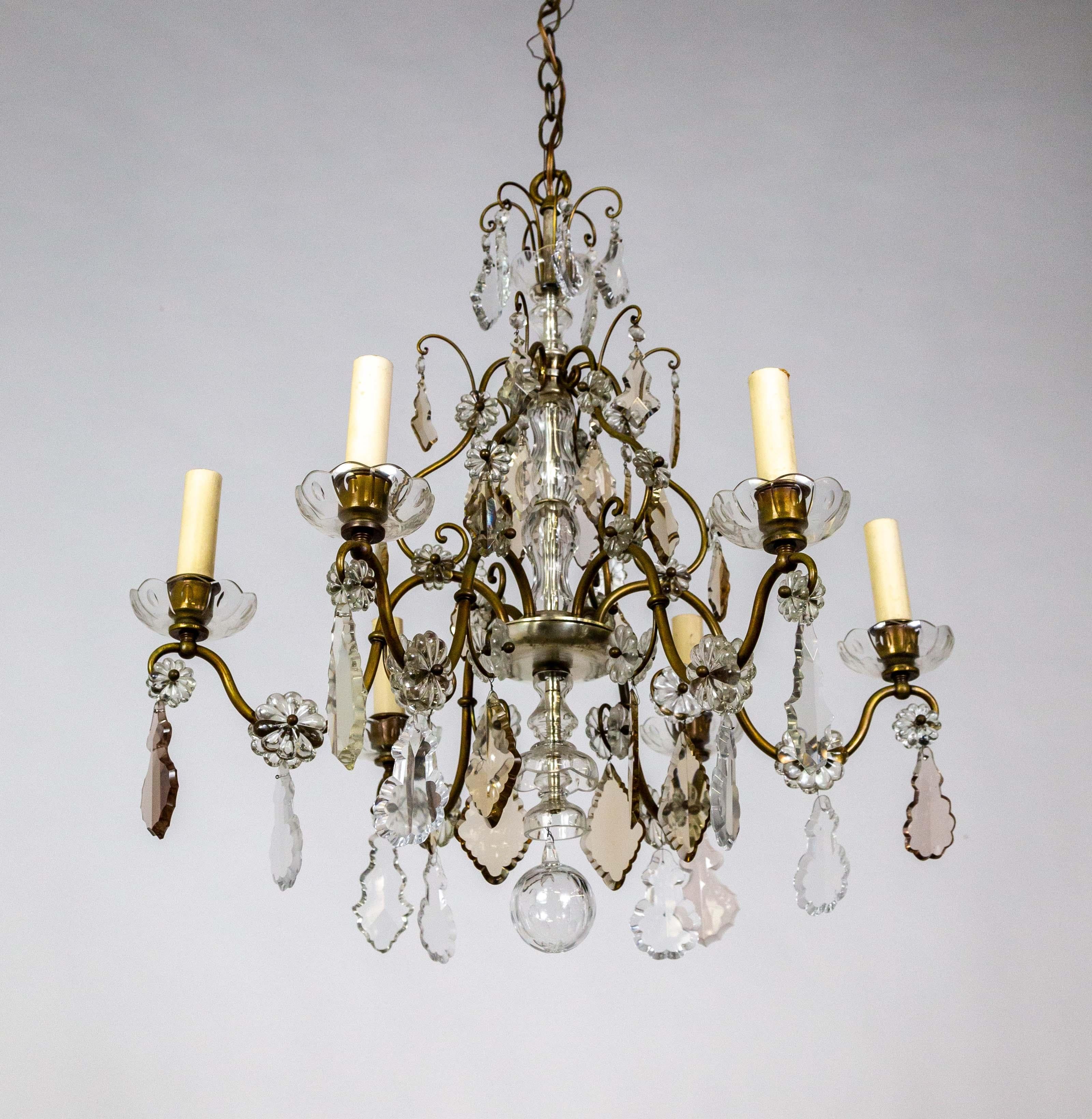 A curling-armed, brass, candlestick style chandelier. The large, finely cut, pendeloque, and scalloped diamond crystals are clear and smoke rose and amber. The brass arms are accented with rosette crystals and a silver-gilt dish body with crystal