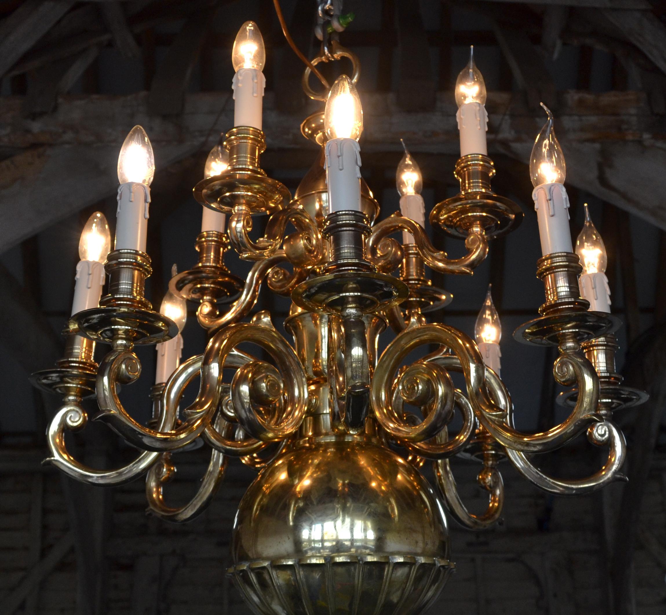 A very rare late Victorian Flemish style solid brass 12 light chandelier. This fixture is of exceptional quality, it has highly decorative scrolled arms cascading on to a unique bottom globe. Half the sphere is decorated with beautiful scalloped
