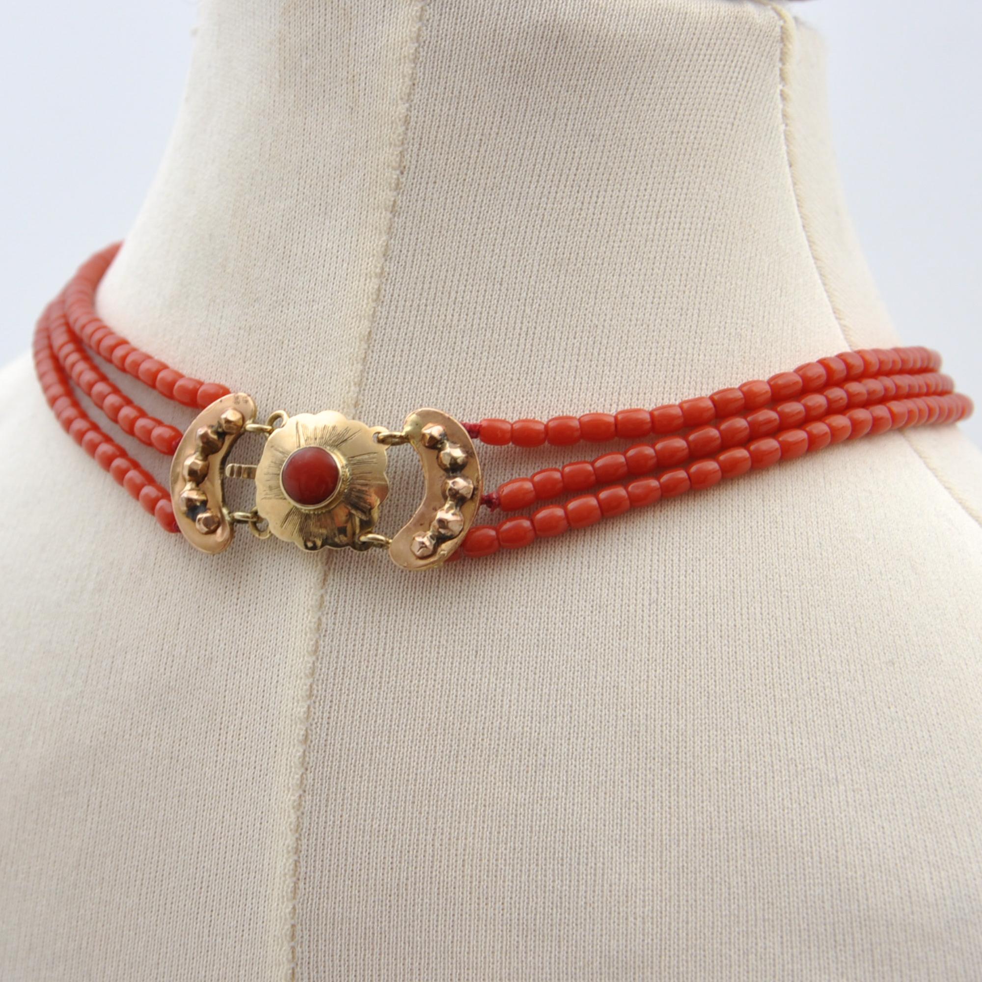 This antique late 19th century coral necklace is created with a 14 karat gold clasp. The beautiful three-strand coral necklace is strung with small coral beads and the strands. The clasp has a beautiful scalloped and engraved design flanked by two