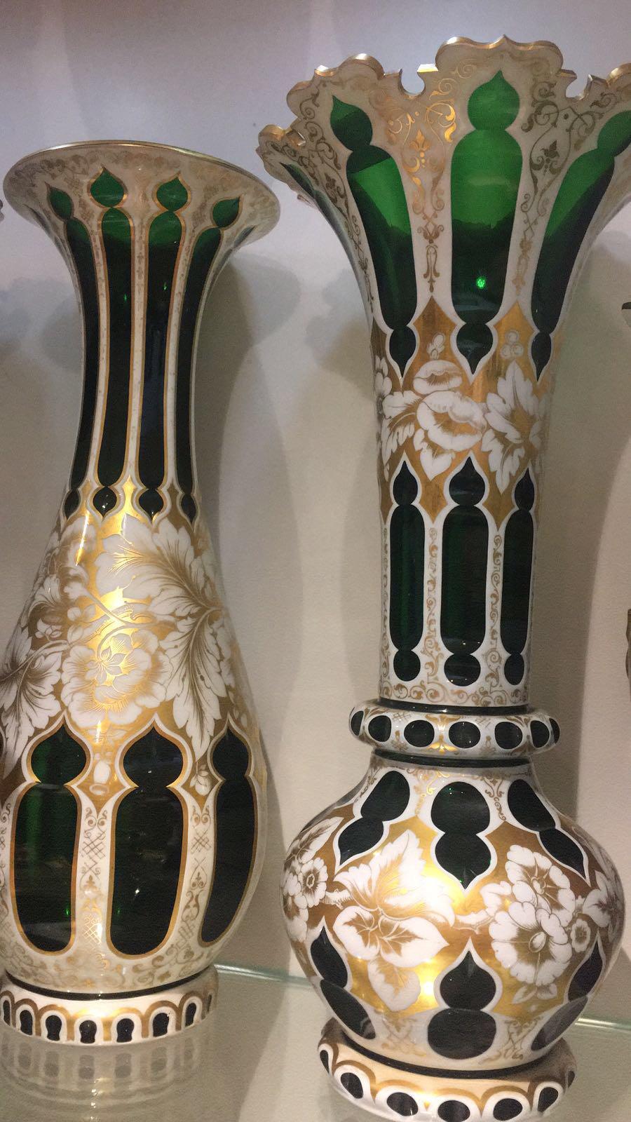 Made of green glass they are enameled in white which is then painted in gold with a floral design, and further gilded in a way to emphasis their design. Two of the glasses are an identical pair and feature a 'Persian' shape of the bottle with a